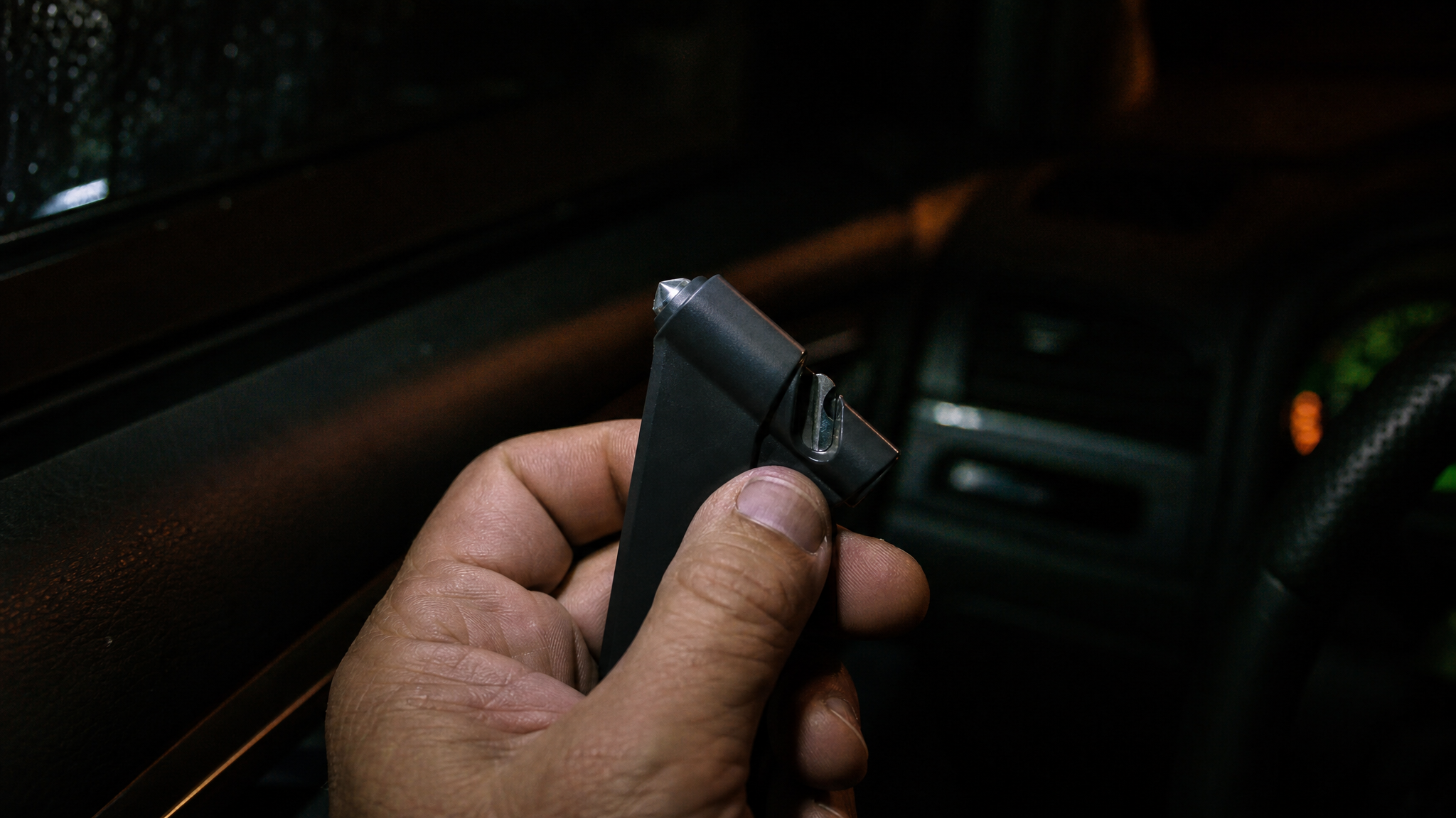 Seatbelt cutter and glass breaker escape tool clipped to a car sun visor for quick access in an emergency
