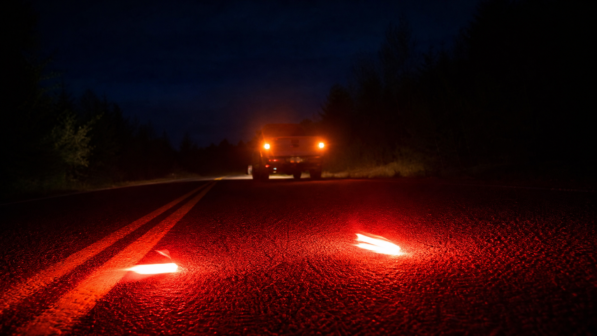 LED road flares lit on dark highway at night behind a disabled truck