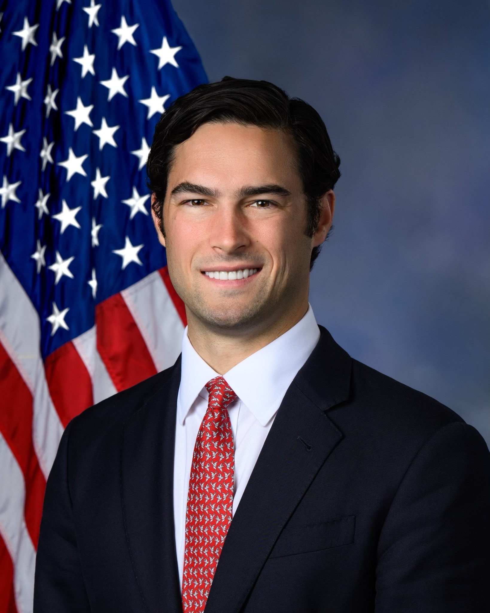 Official congressional portrait of Representative Brandon Gill of Texas in a dark suit and red tie in front of an American flag