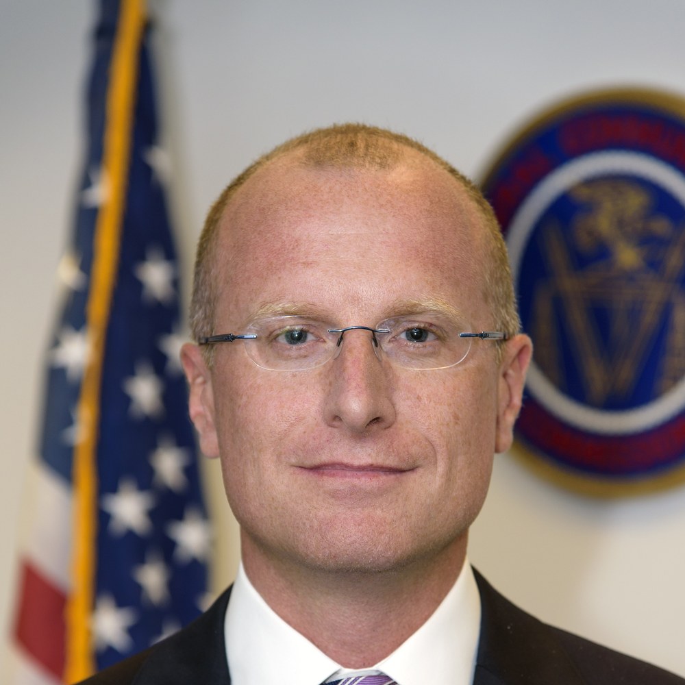 FCC Chairman Brendan Carr in front of the American flag and the FCC seal