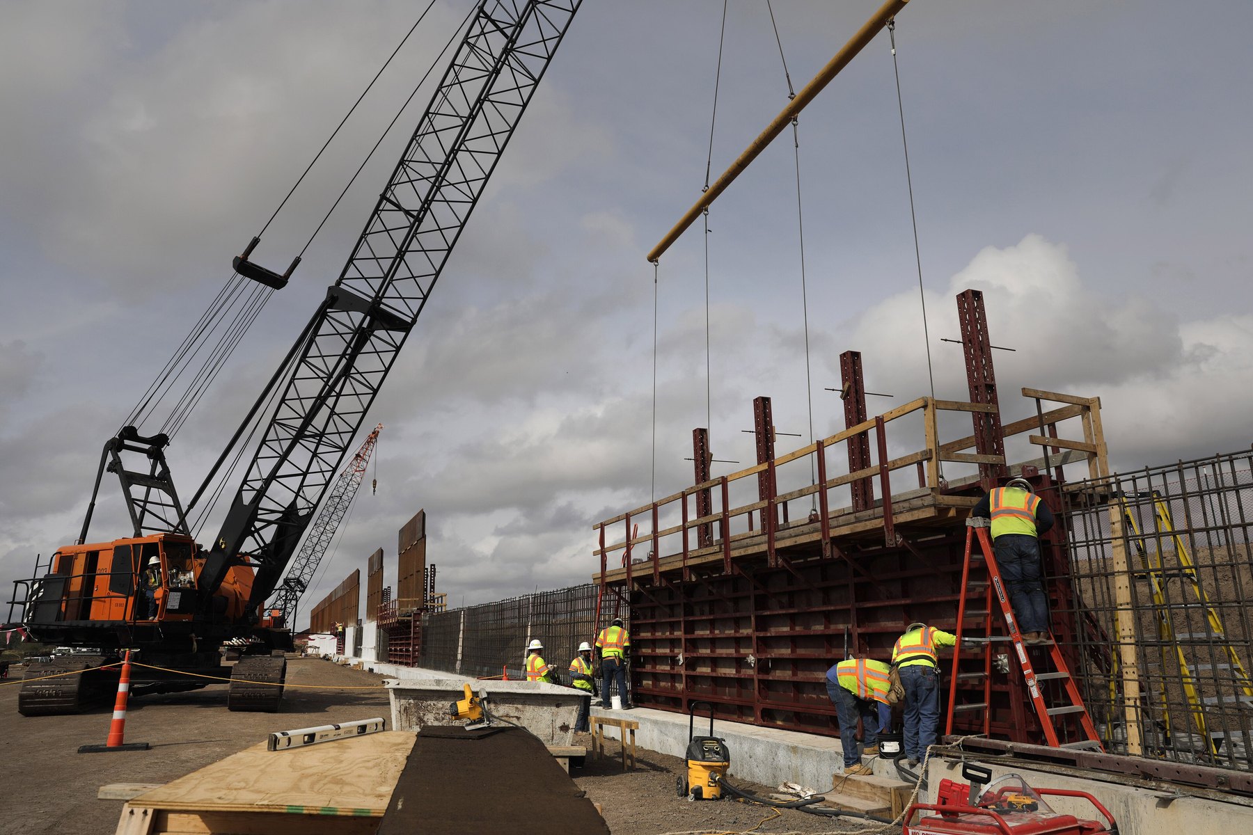 Crews and a crane build a concrete border wall system near Weslaco, Texas