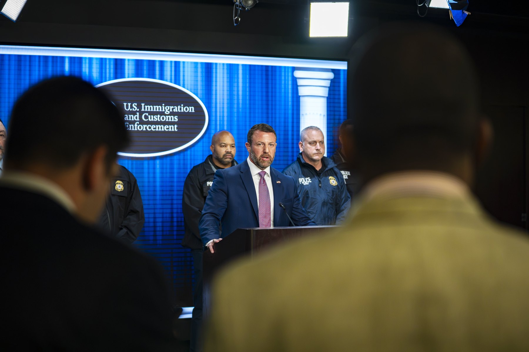 Homeland Security Secretary Markwayne Mullin speaking at a podium during an ICE press conference in Washington