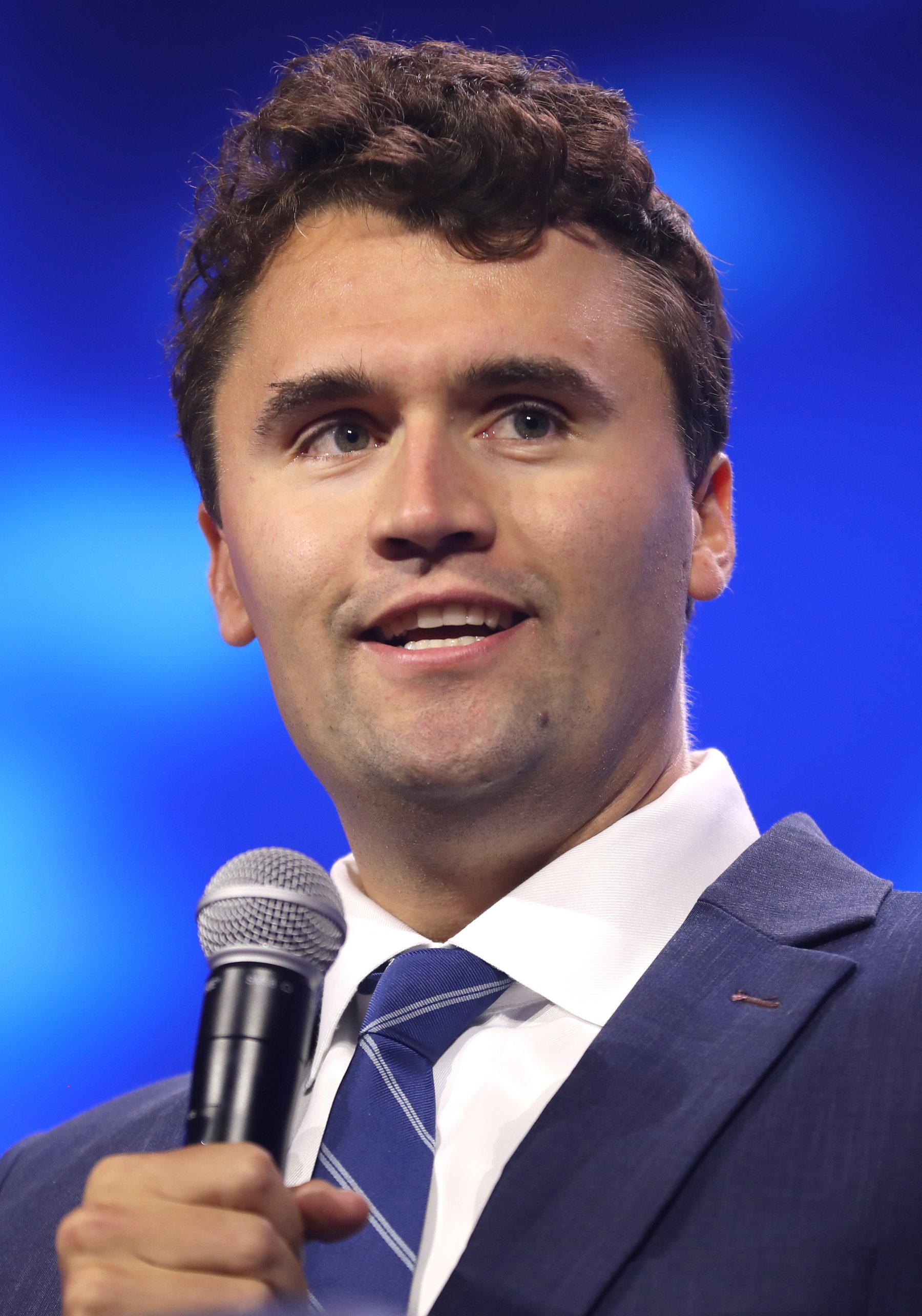 Charlie Kirk speaking into a microphone at a Turning Point USA event