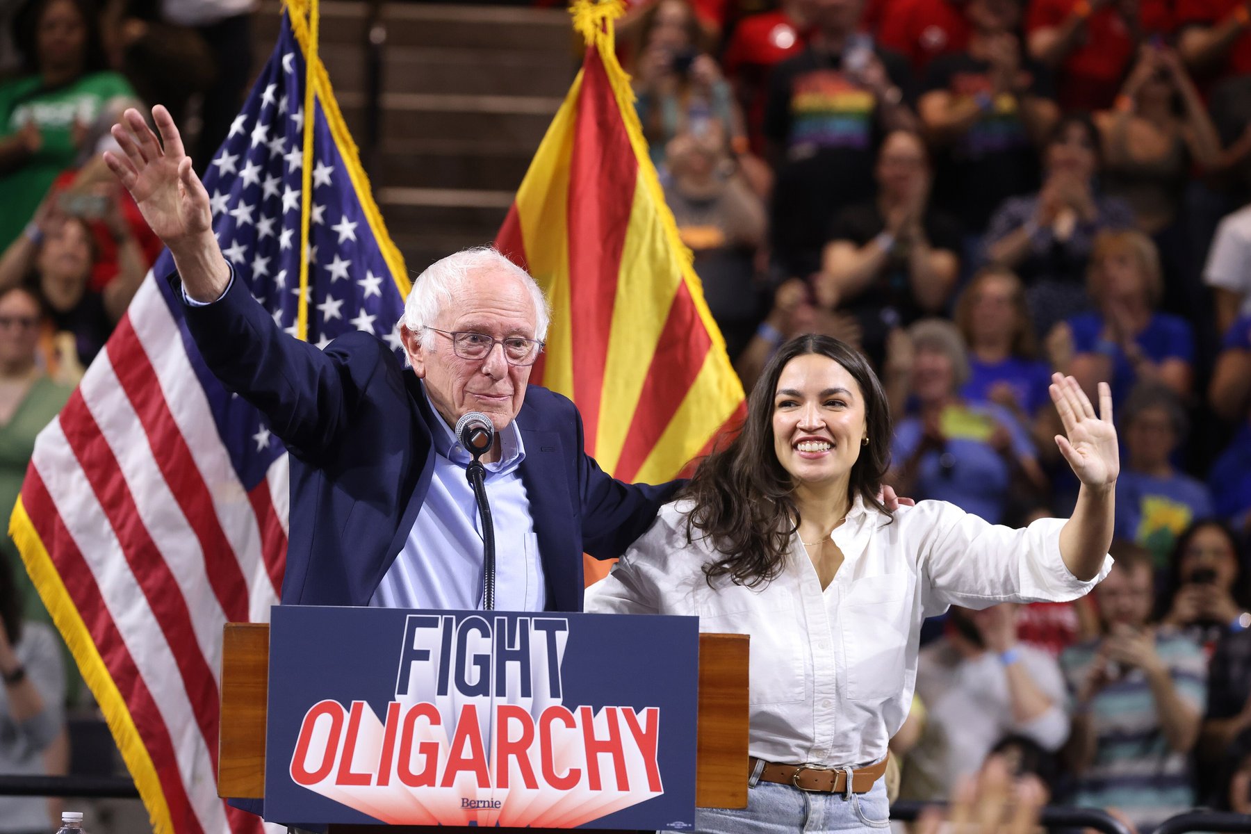 Senator Bernie Sanders and Representative Alexandria Ocasio-Cortez waving to a crowd at a Fight Oligarchy rally in Tempe, Arizona