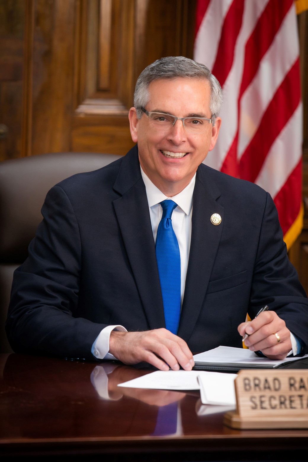 Official portrait of Georgia Secretary of State Brad Raffensperger seated at his desk