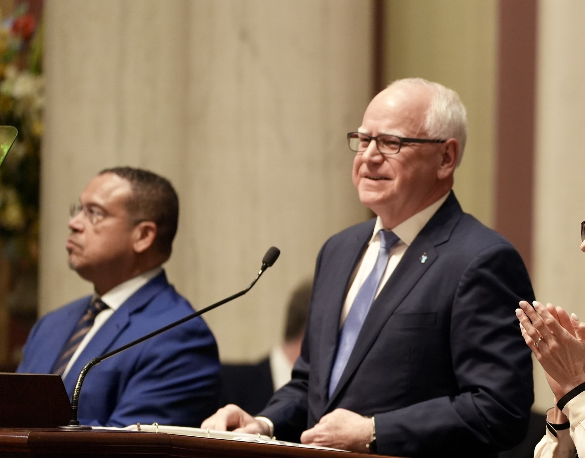 Minnesota Attorney General Keith Ellison seated at left and Gov. Tim Walz at the rostrum during the 2025 State of the State address