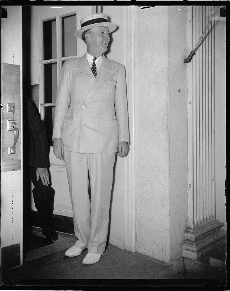Justice Hugo Black standing in a doorway in a light suit and straw hat, August 1937