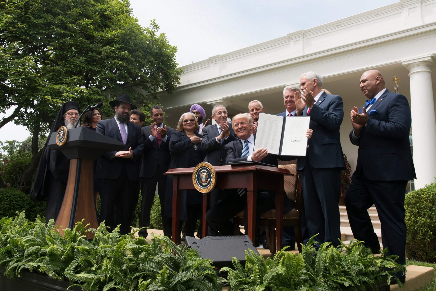 President Donald Trump displays his signed Executive Order Promoting Free Speech and Religious Liberty in the Rose Garden on May 4, 2017, surrounded by religious leaders