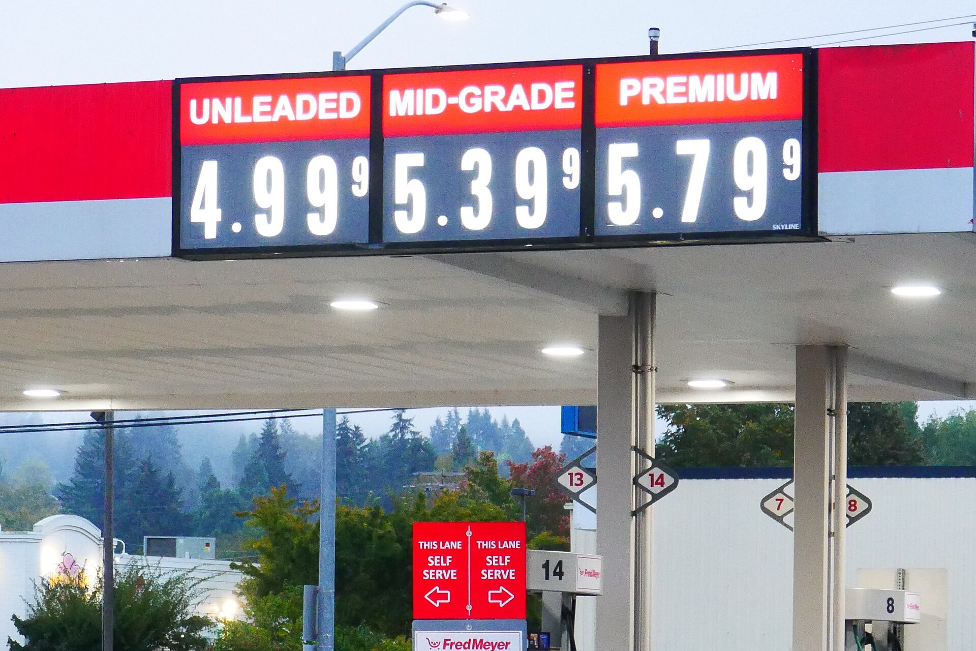 Fuel station price sign showing unleaded at $4.99 9/10, mid-grade at $5.39 9/10 and premium at $5.79 9/10 above the pumps