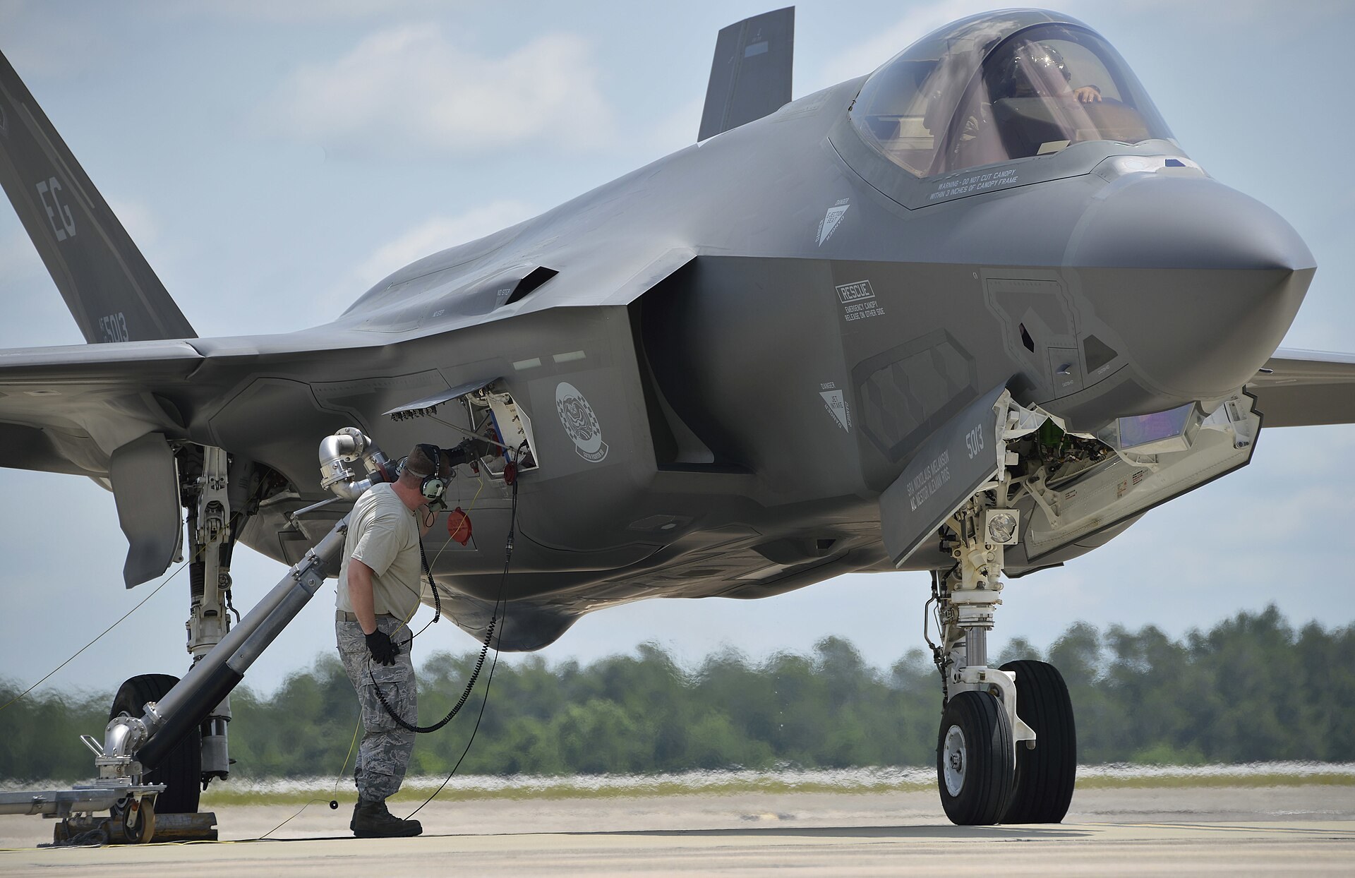 An Air Force maintainer stands beside an F-35A on the ramp during a hot pit refuel at Eglin Air Force Base