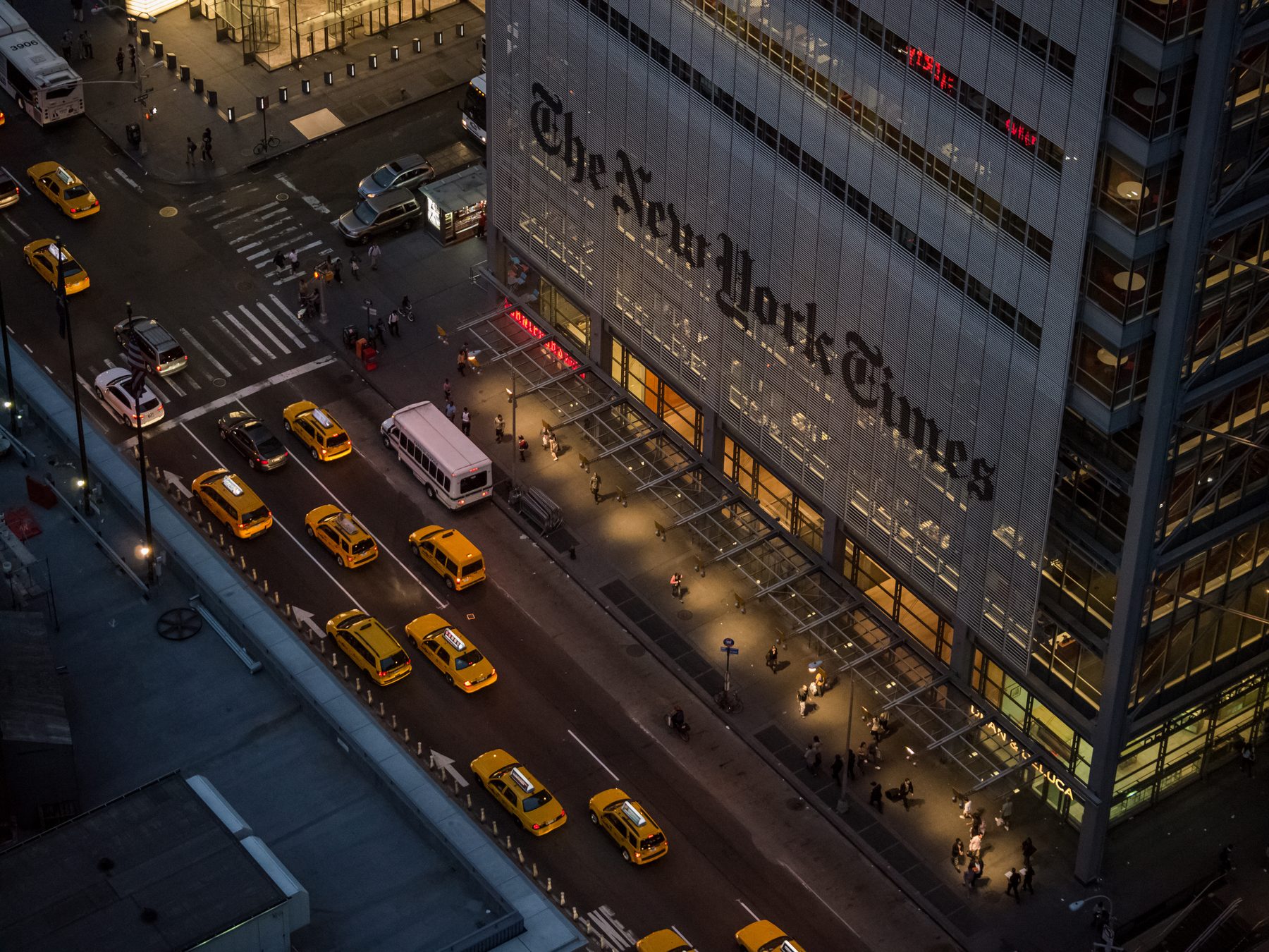The New York Times Building on Eighth Avenue in Manhattan at dusk, seen from above, with yellow taxis on the street