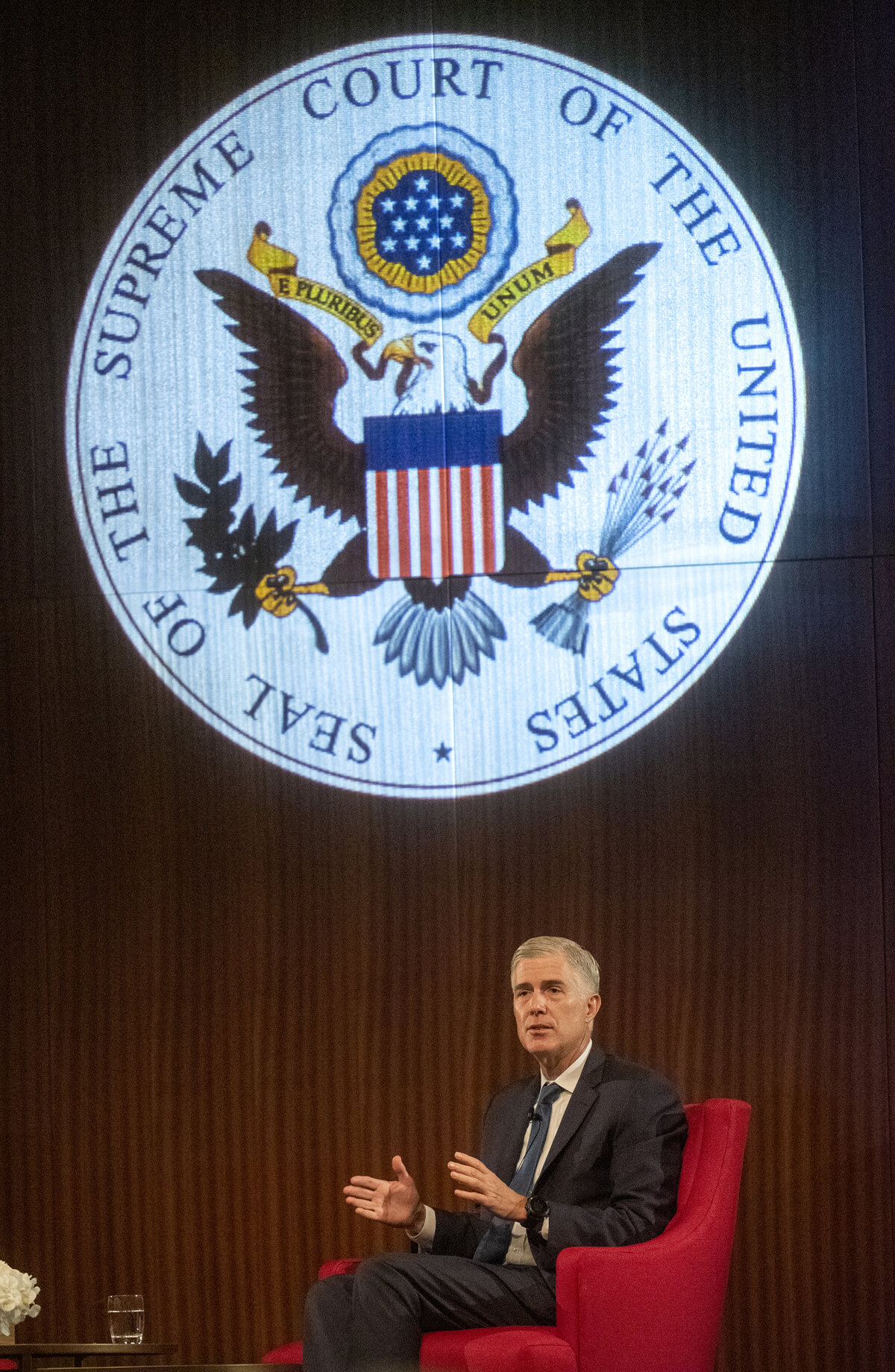 Justice Neil Gorsuch speaking at a 2019 event beneath the Supreme Court seal