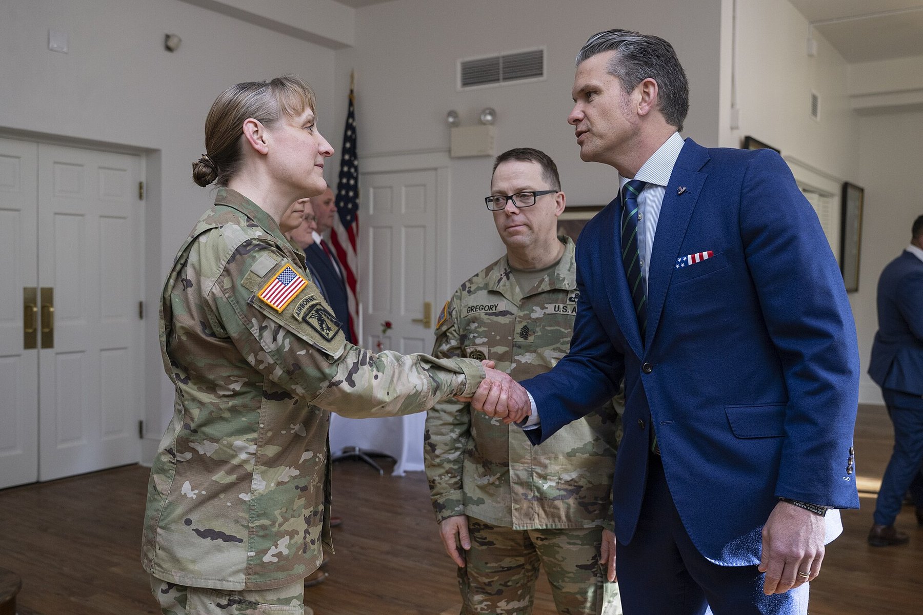 Defense Secretary Pete Hegseth in a blue suit shaking hands with a uniformed Army officer at the U.S. Army War College