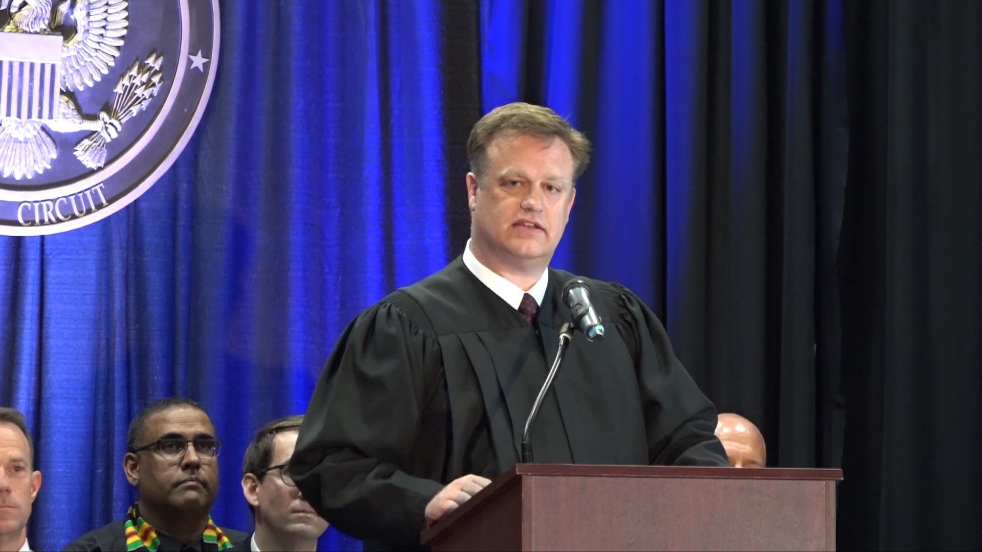 Ninth Circuit Judge Ryan D. Nelson speaking at a podium
