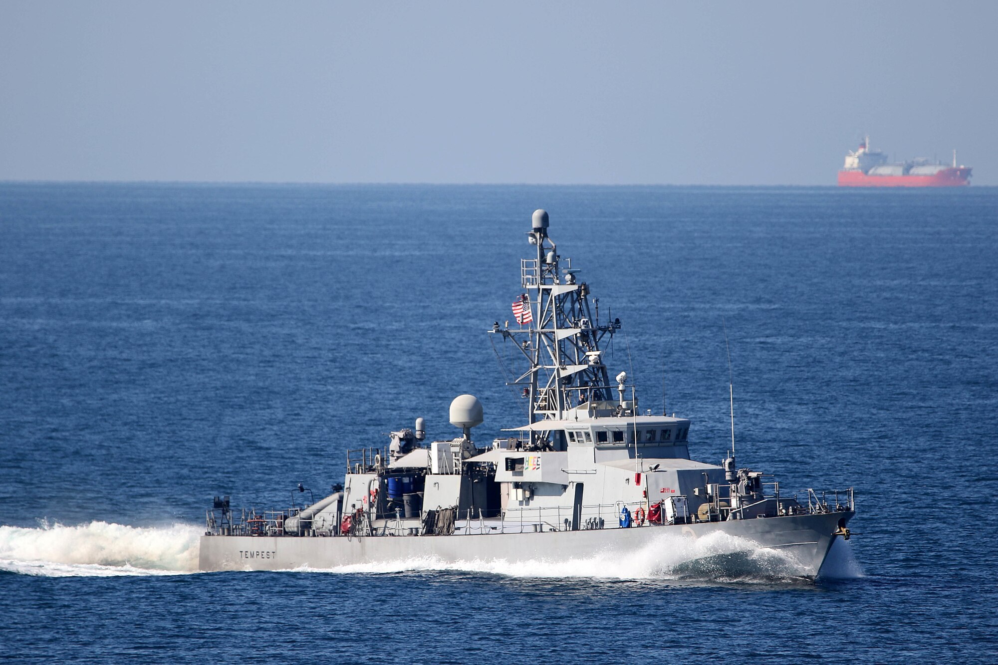The coastal patrol ship USS Tempest underway in the Strait of Hormuz with a tanker on the horizon