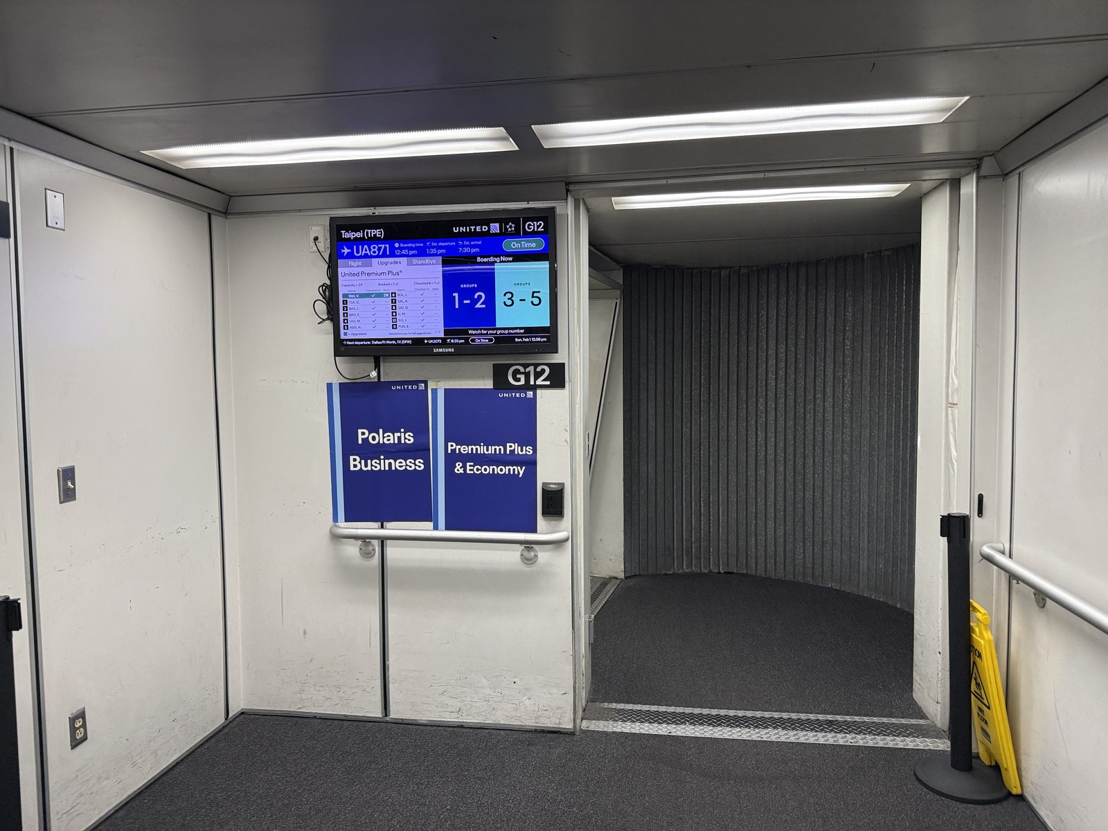 The entrance to a jet bridge at gate G12 at San Francisco International Airport, with a United Airlines boarding display overhead
