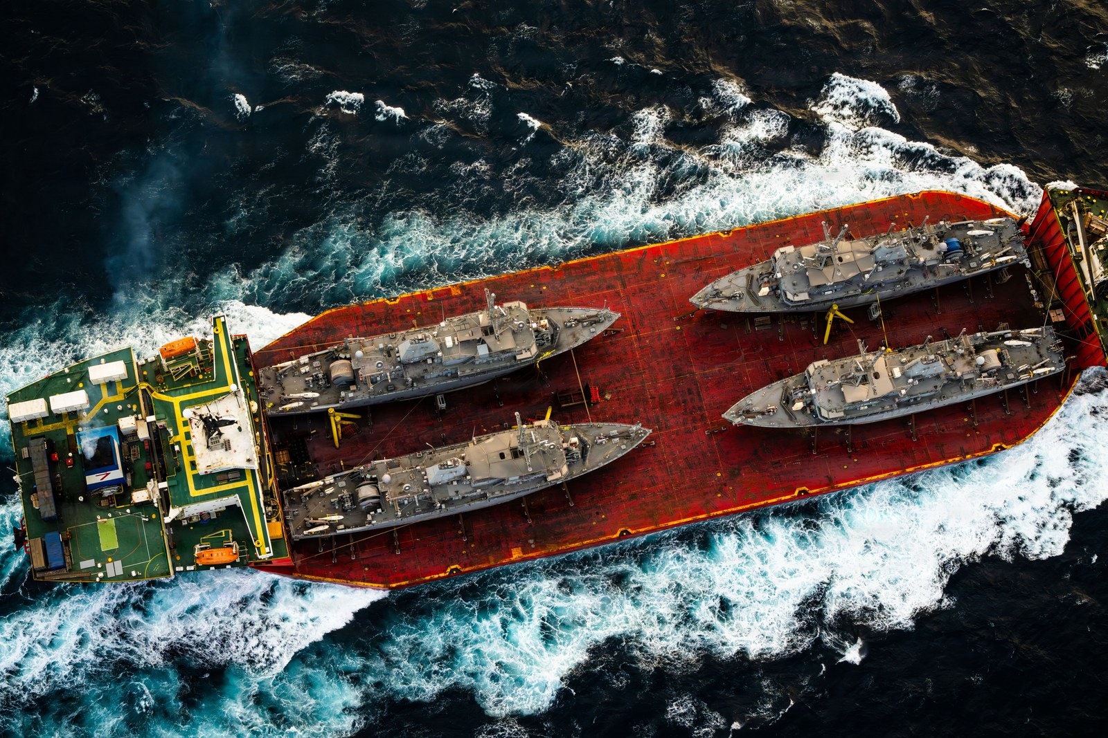 Aerial view of the merchant vessel Seaway Hawk carrying four decommissioned U.S. Navy Avenger-class mine countermeasures ships on its deck in the Arabian Gulf