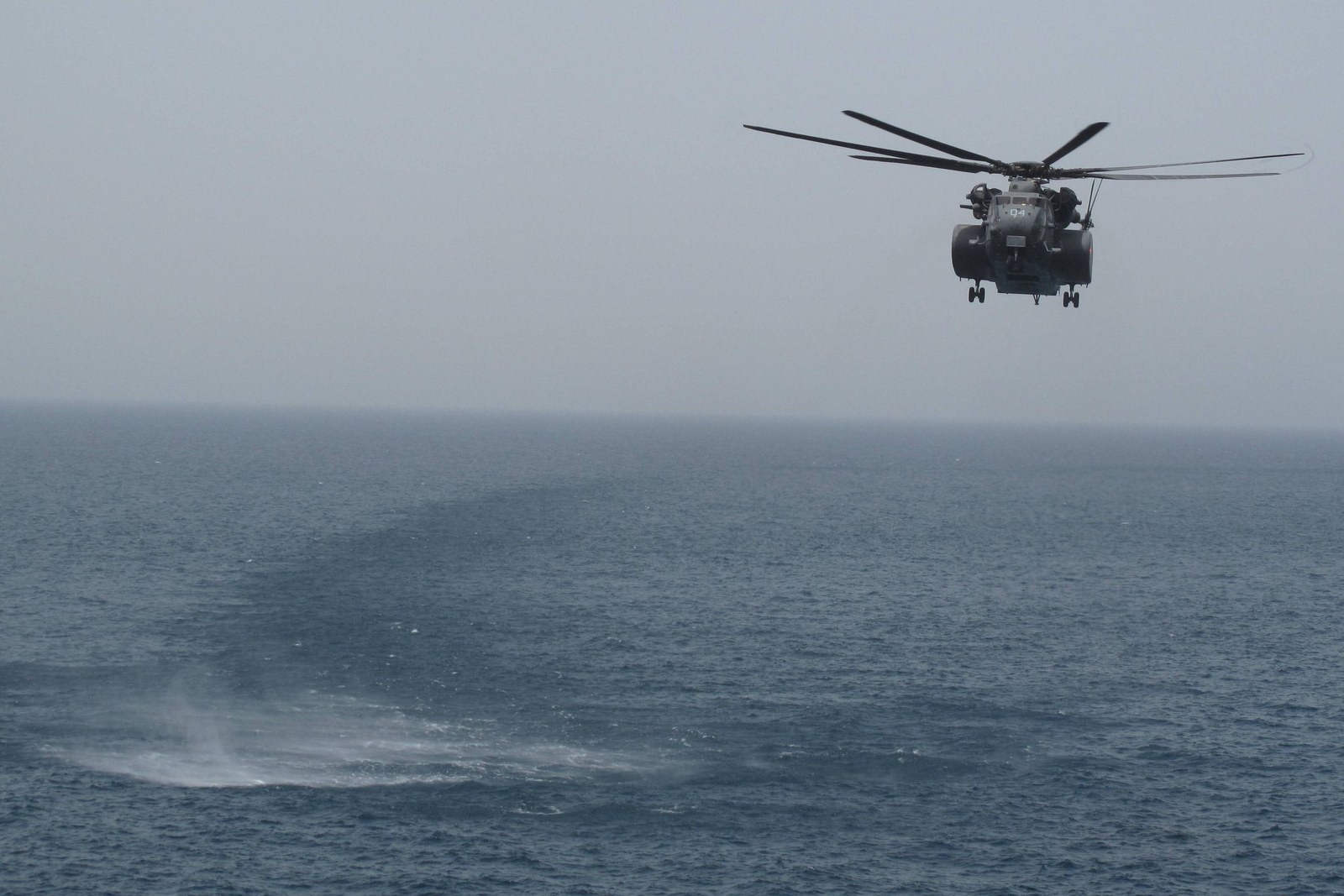 An MH-53E Sea Dragon mine countermeasures helicopter flying low over the water in the U.S. 5th Fleet area of responsibility