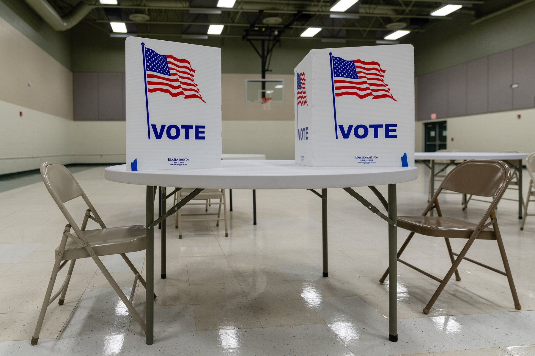 Two tabletop voting booths with American flags and the word VOTE inside a church gym polling place in Grand Rapids, Minnesota