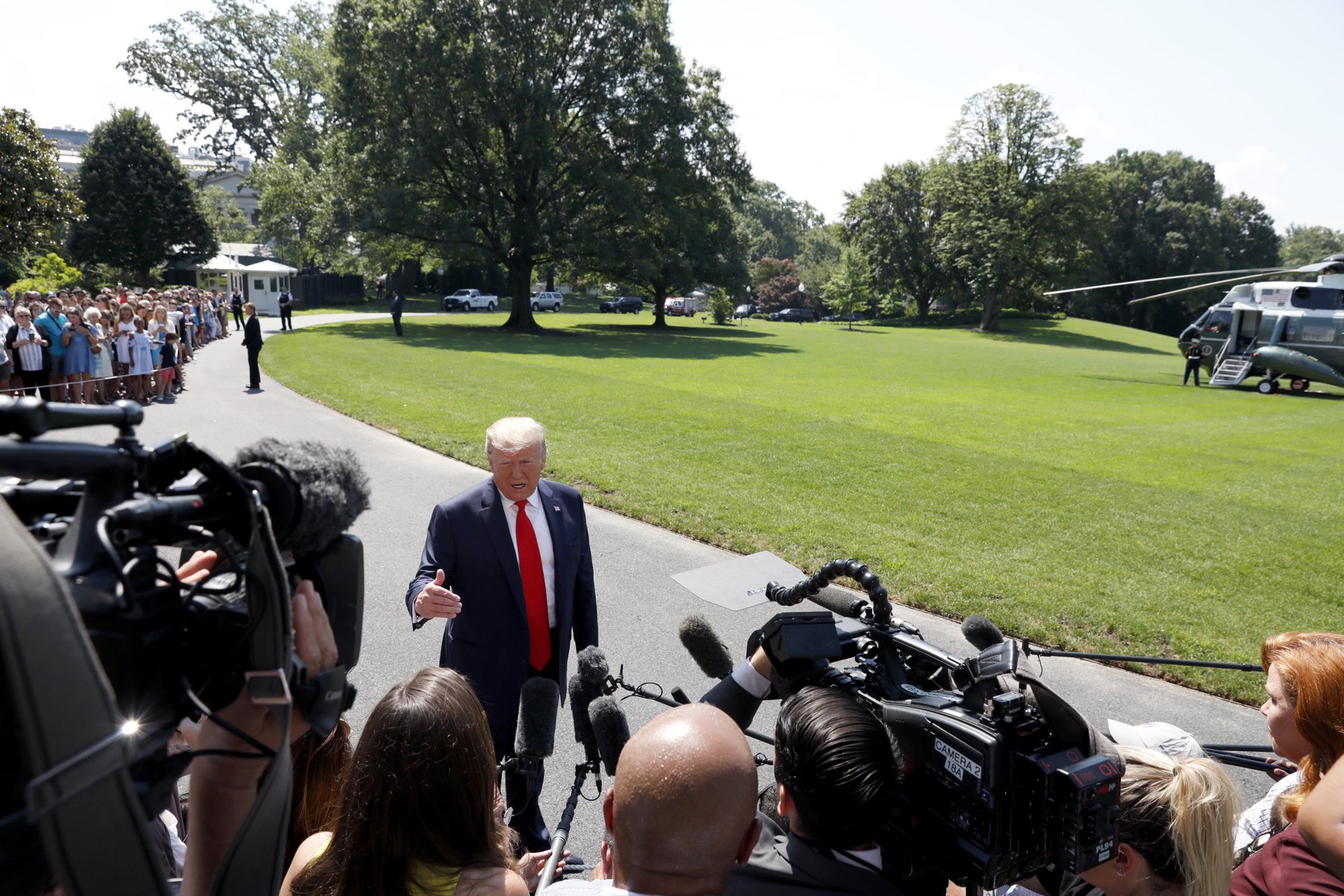 President Trump speaking to a crowd of reporters and TV cameras on the South Lawn of the White House, with Marine One in the background