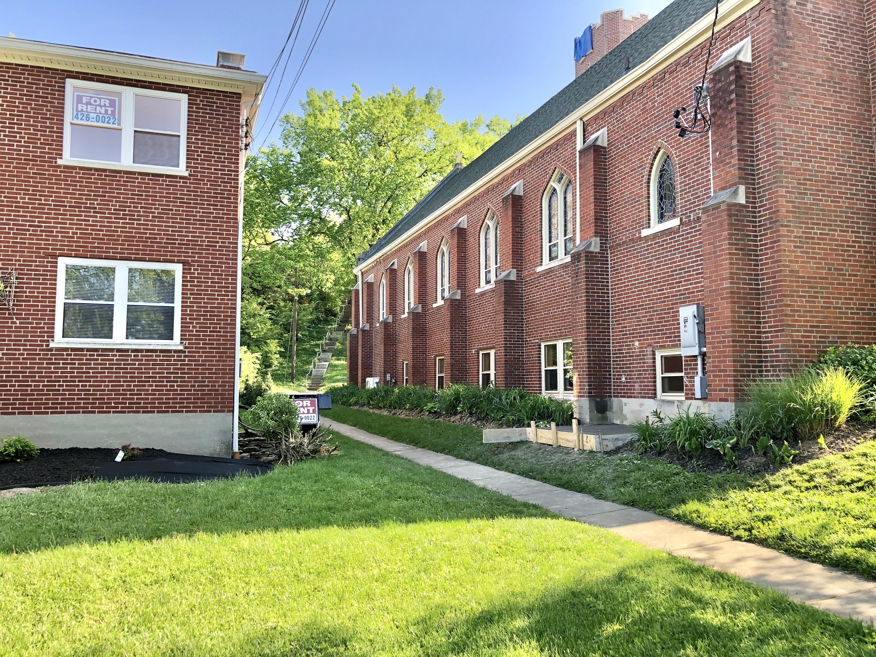 Side wall of Our Lady of Lourdes church in Park Hills beside a neighboring brick apartment building