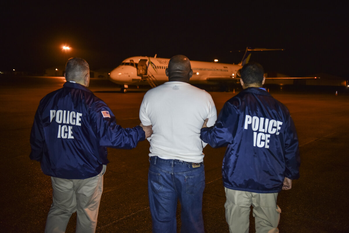 ICE Enforcement and Removal Operations officers escort a detainee to a removal flight
