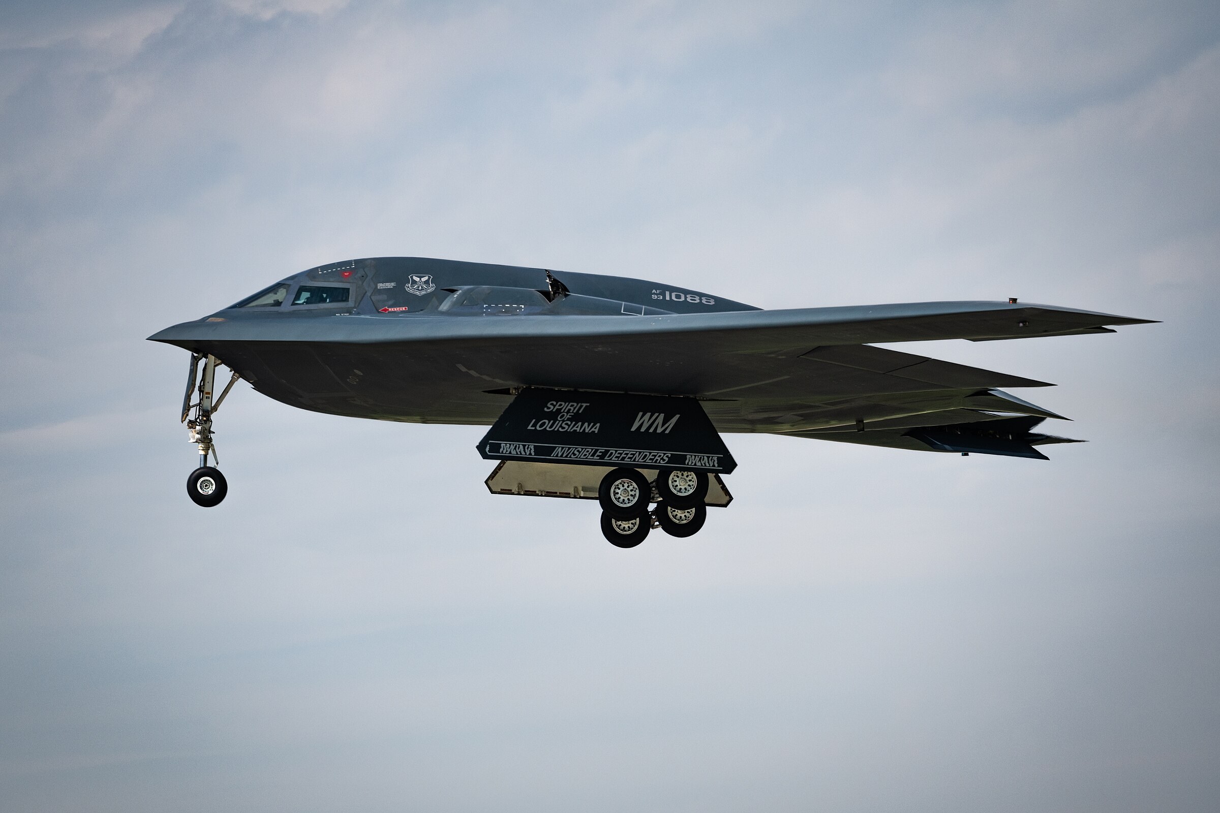 A B-2 Spirit stealth bomber marked Spirit of Louisiana in flight with landing gear down