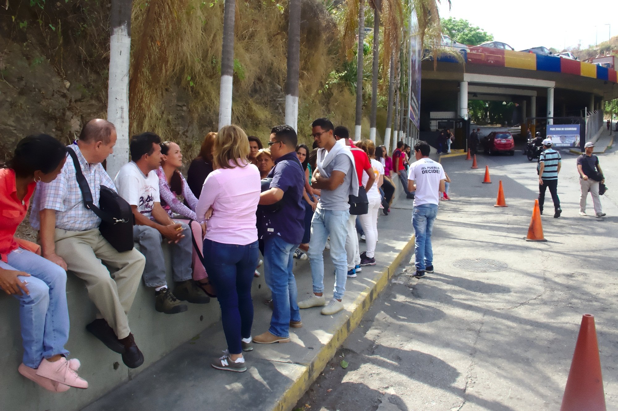 Relatives of political prisoners waiting outside El Helicoide in Caracas, one man wearing a shirt reading Preso Politico