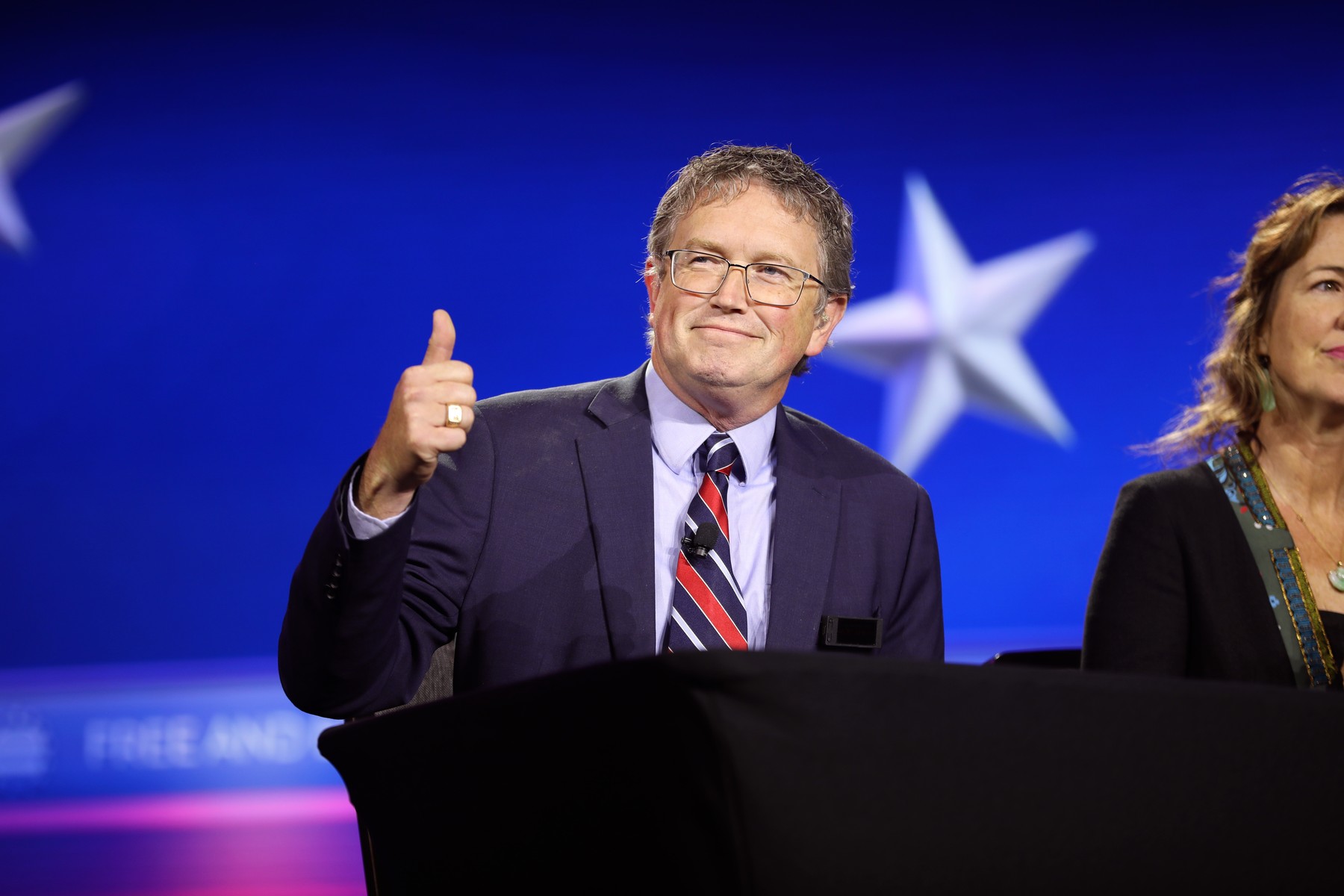 Rep. Thomas Massie, R-Ky., speaking with attendees at a 2024 event, wearing glasses and giving a thumbs-up gesture