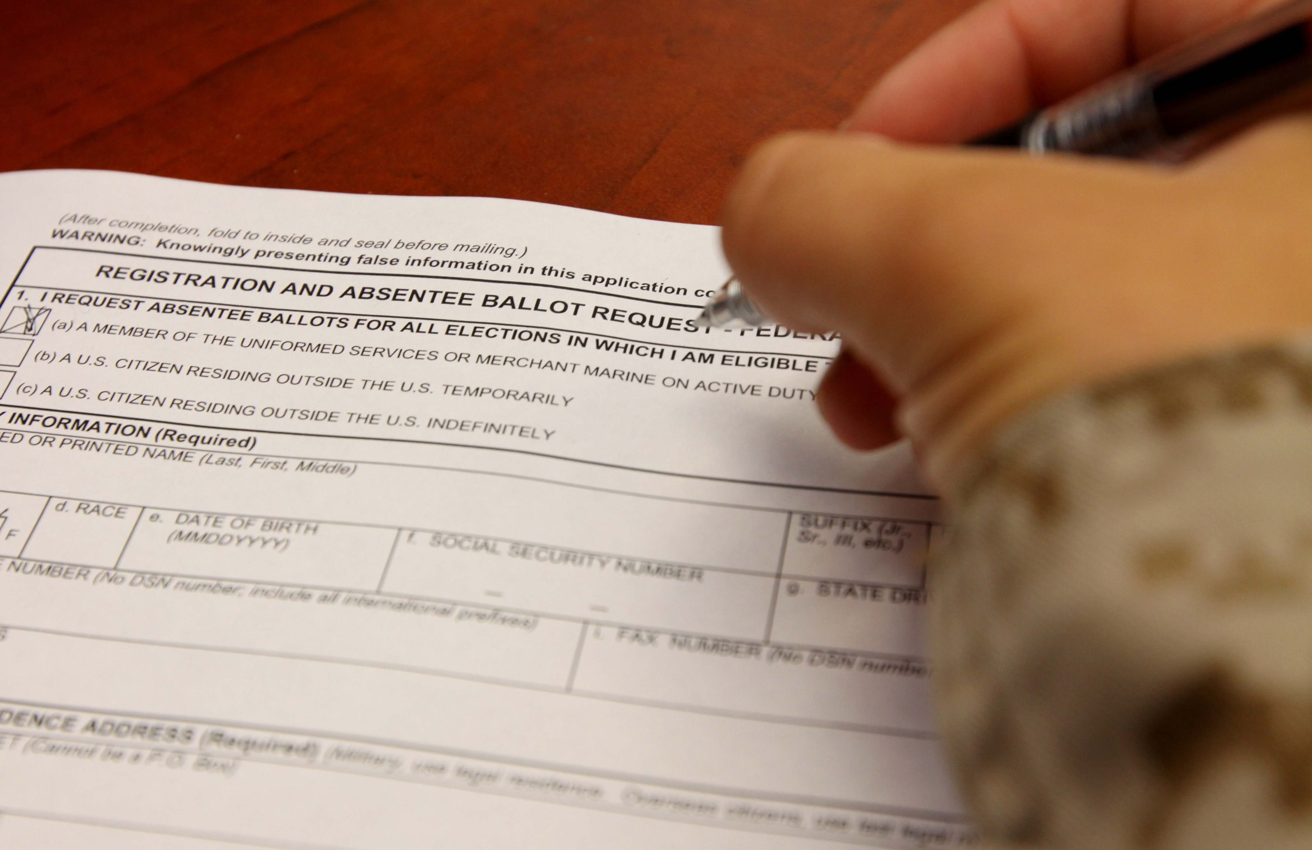 A service member fills out a Federal Post Card Application to request an absentee ballot