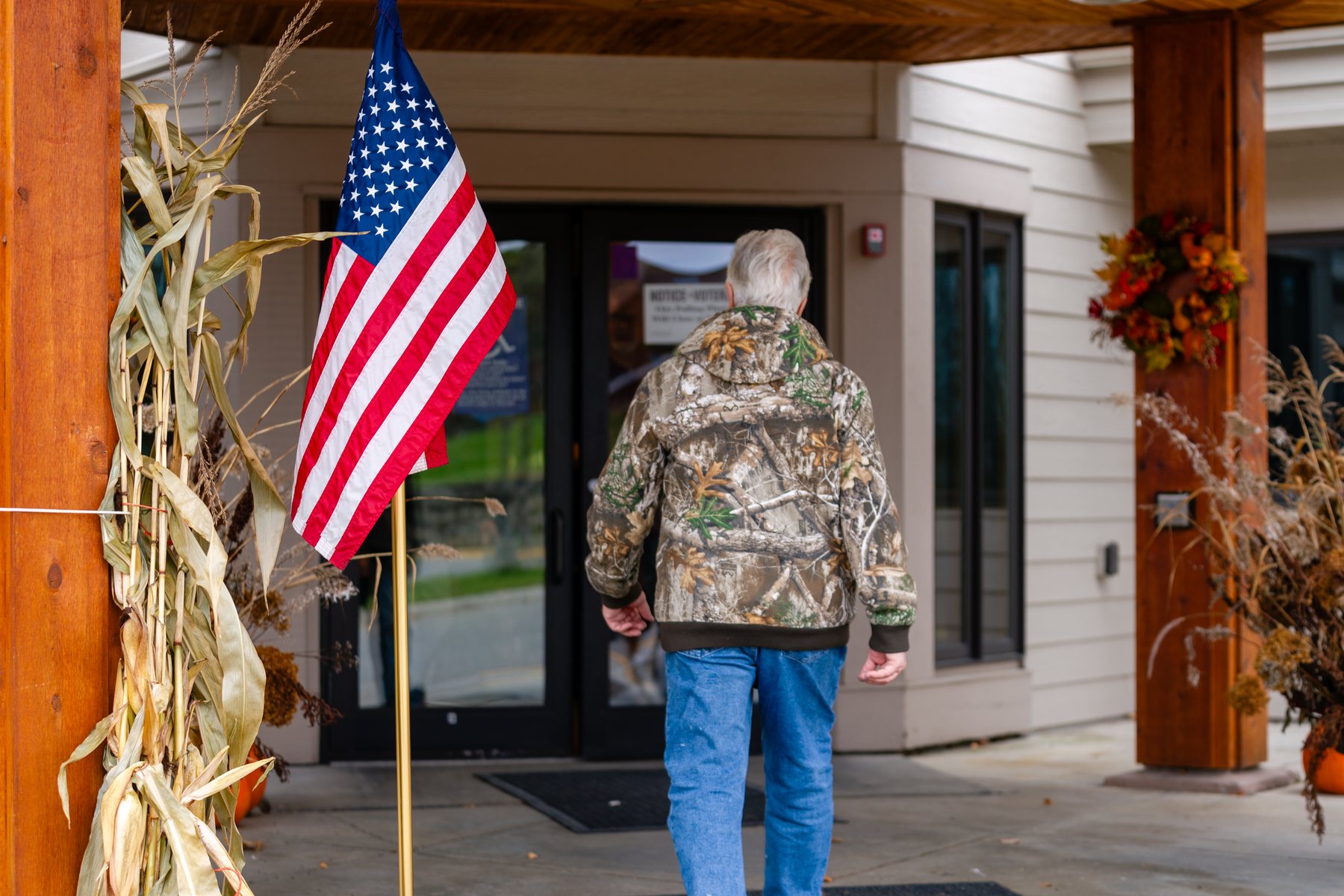 A voter in a camouflage jacket walks past an American flag into a polling place at Zion Lutheran Church in Grand Rapids, Minnesota, on Election Day
