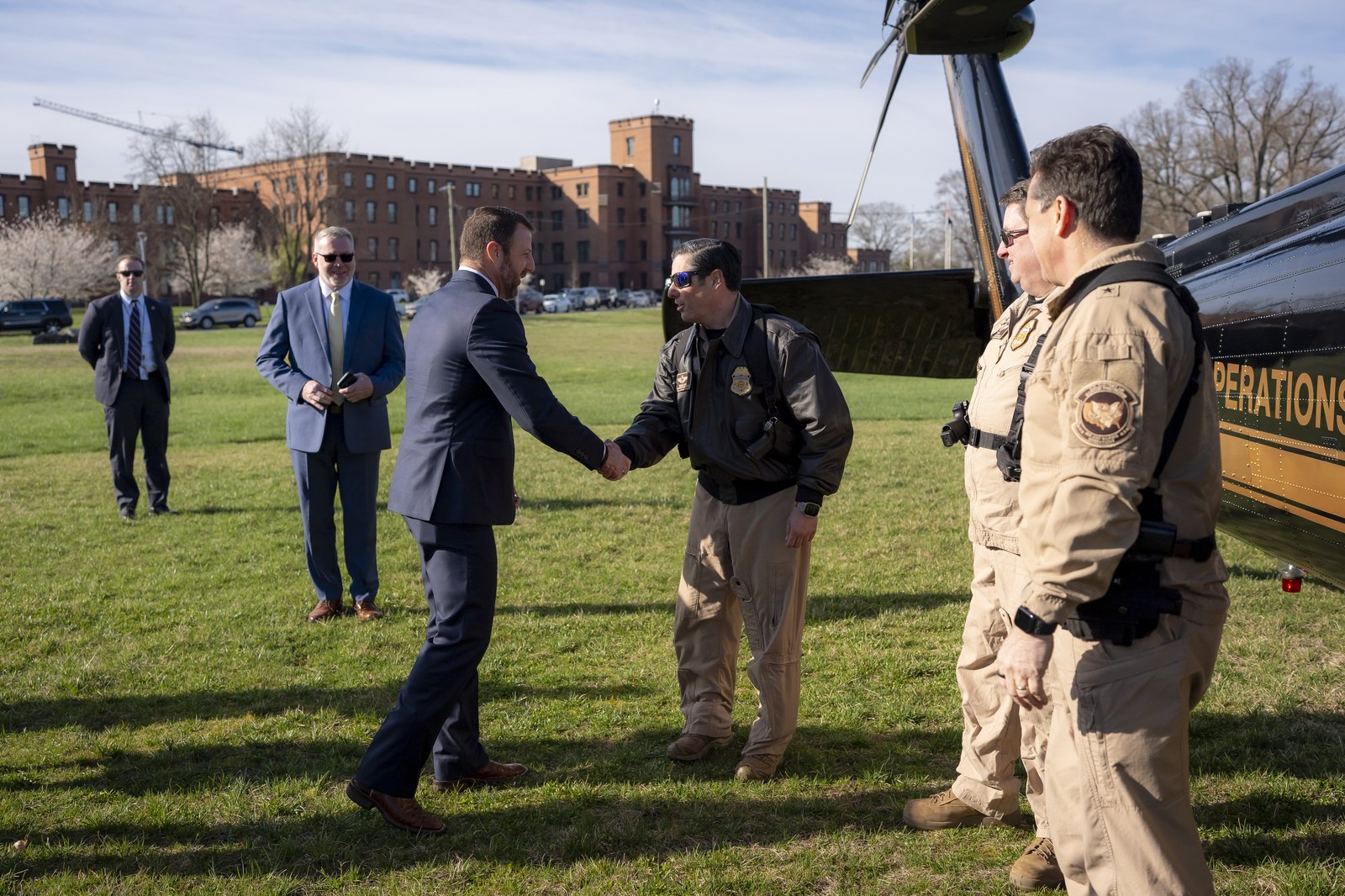 Homeland Security Secretary Markwayne Mullin shakes hands with a federal law enforcement officer beside a helicopter at the DHS St. Elizabeths campus in Washington