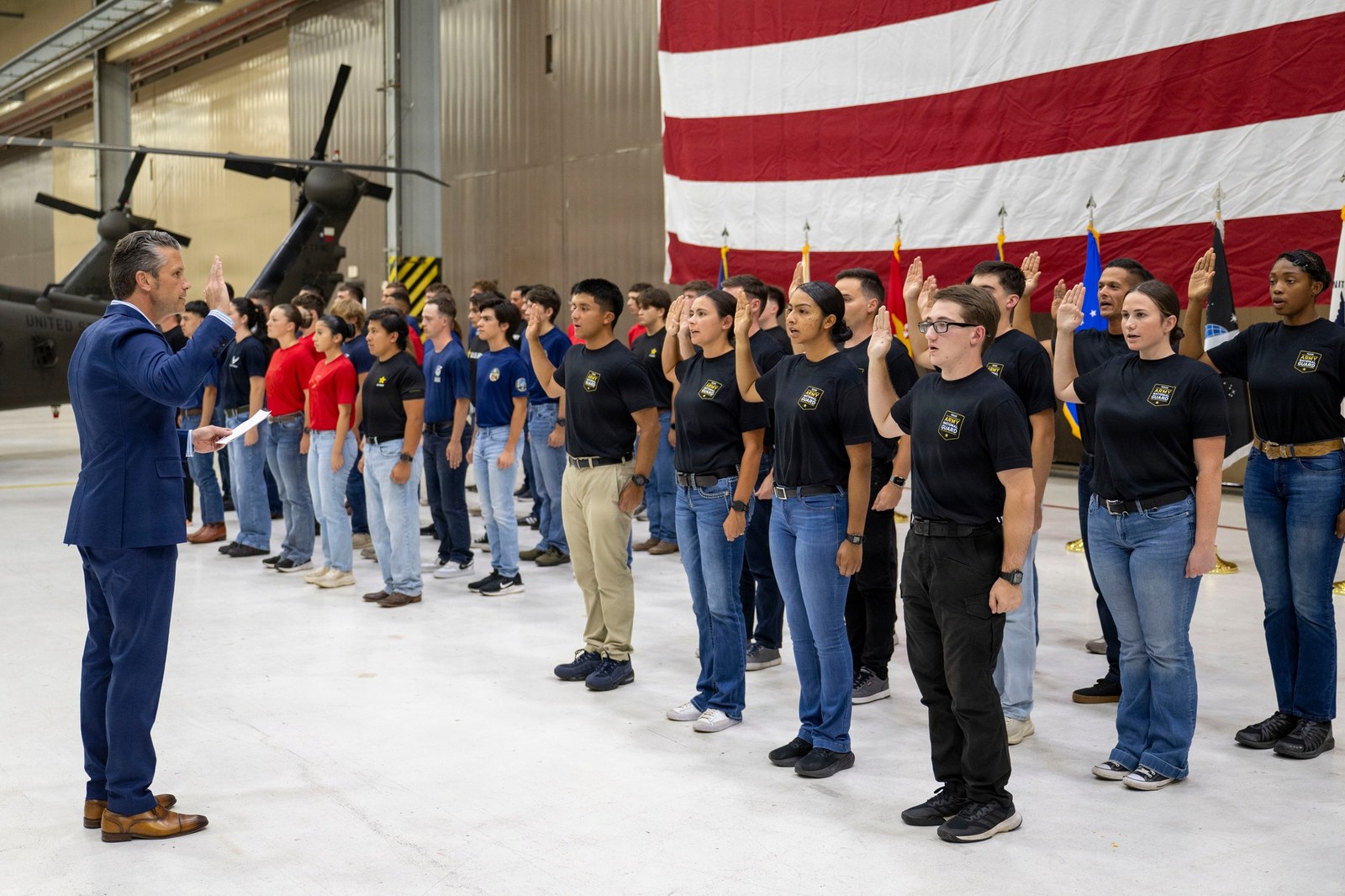 Secretary of War Pete Hegseth administers the oath of enlistment to a group of young recruits inside a military hangar in Austin, Texas