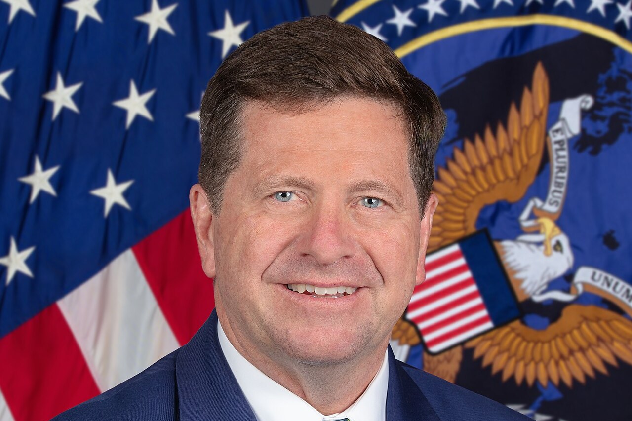 Official portrait of Director of National Intelligence Jay Clayton in front of a U.S. flag and the ODNI seal