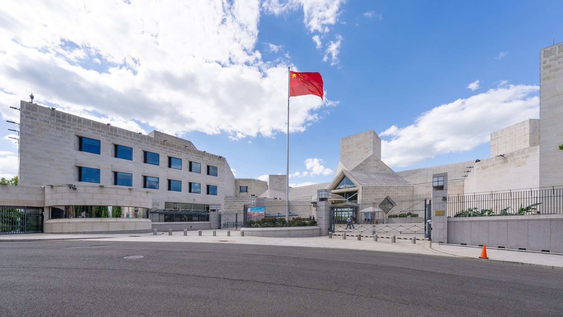 Wide view of the Embassy of the People's Republic of China in Washington, D.C., with the sidewalk and street in front of its fence