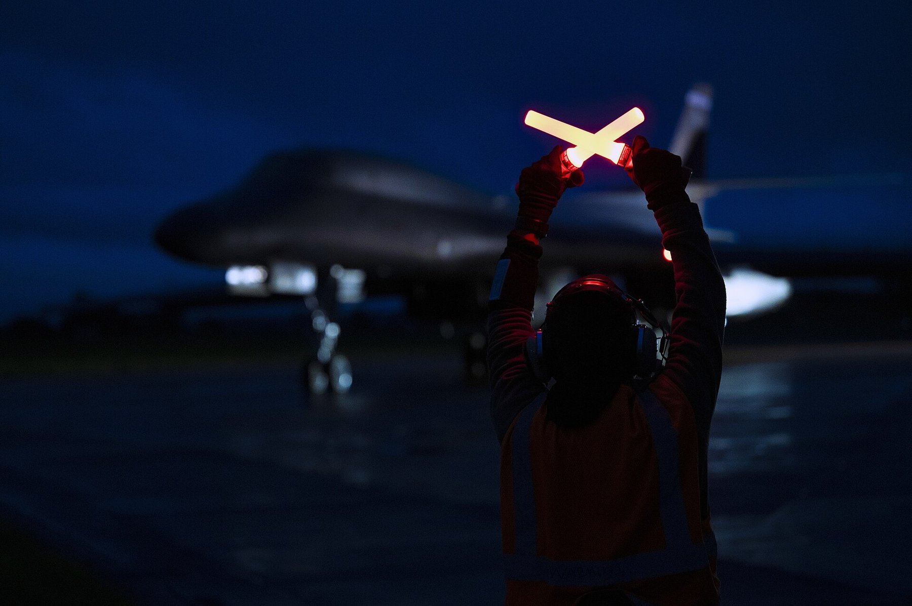 U.S. Air Force crew chief standing beside a B-1B Lancer on the flight line at RAF Fairford at night