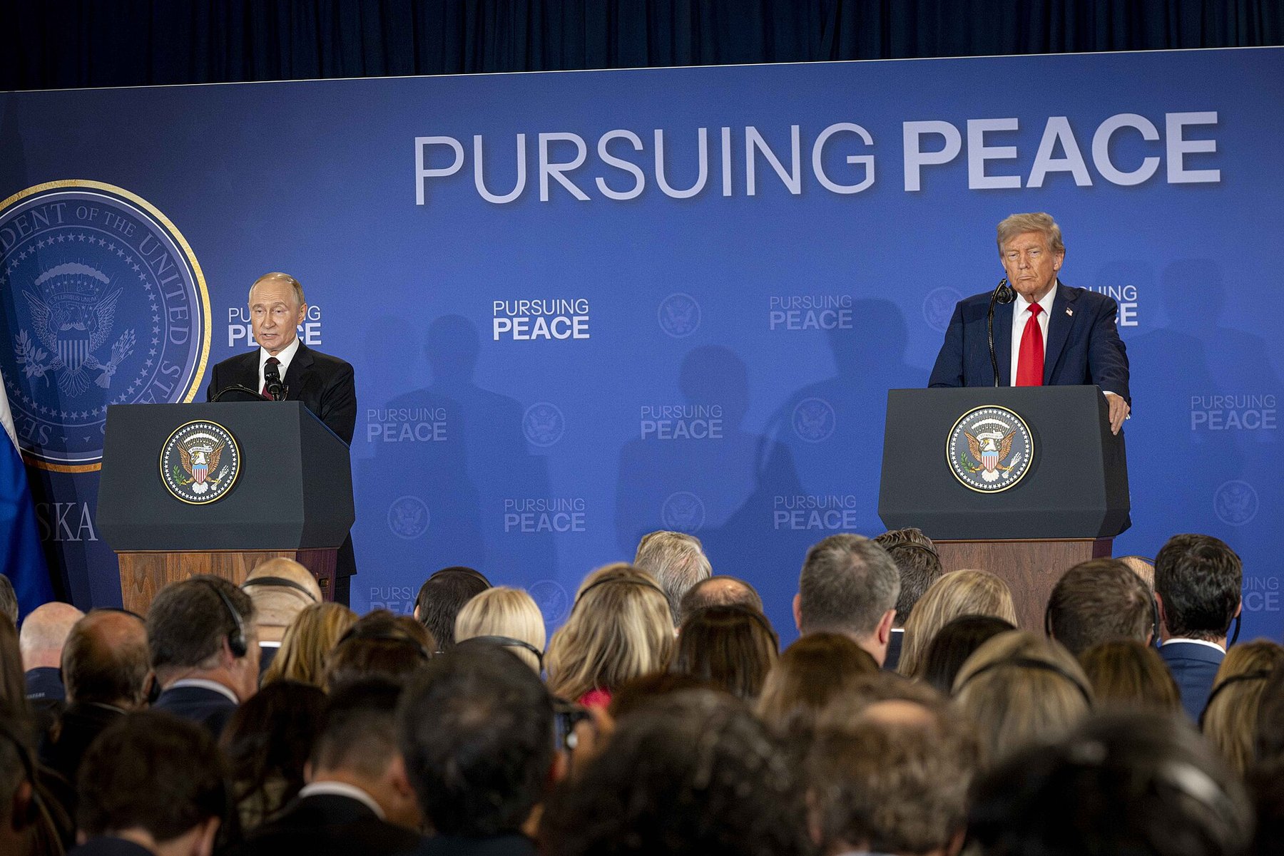 Vladimir Putin and Donald Trump at podiums during their joint press conference at Joint Base Elmendorf-Richardson in Anchorage, Alaska