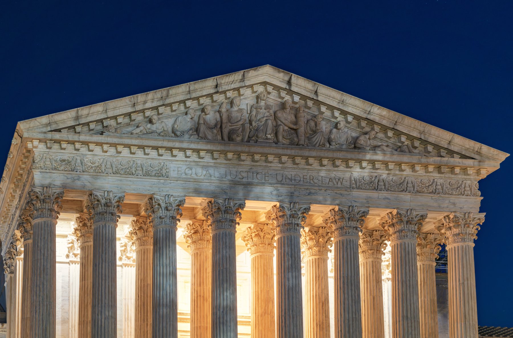 The west facade of the United States Supreme Court Building at night, with the words Equal Justice Under Law above the columns