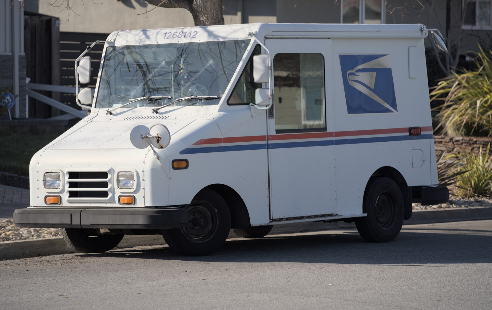 A United States Postal Service Grumman LLV delivery truck parked on a residential street