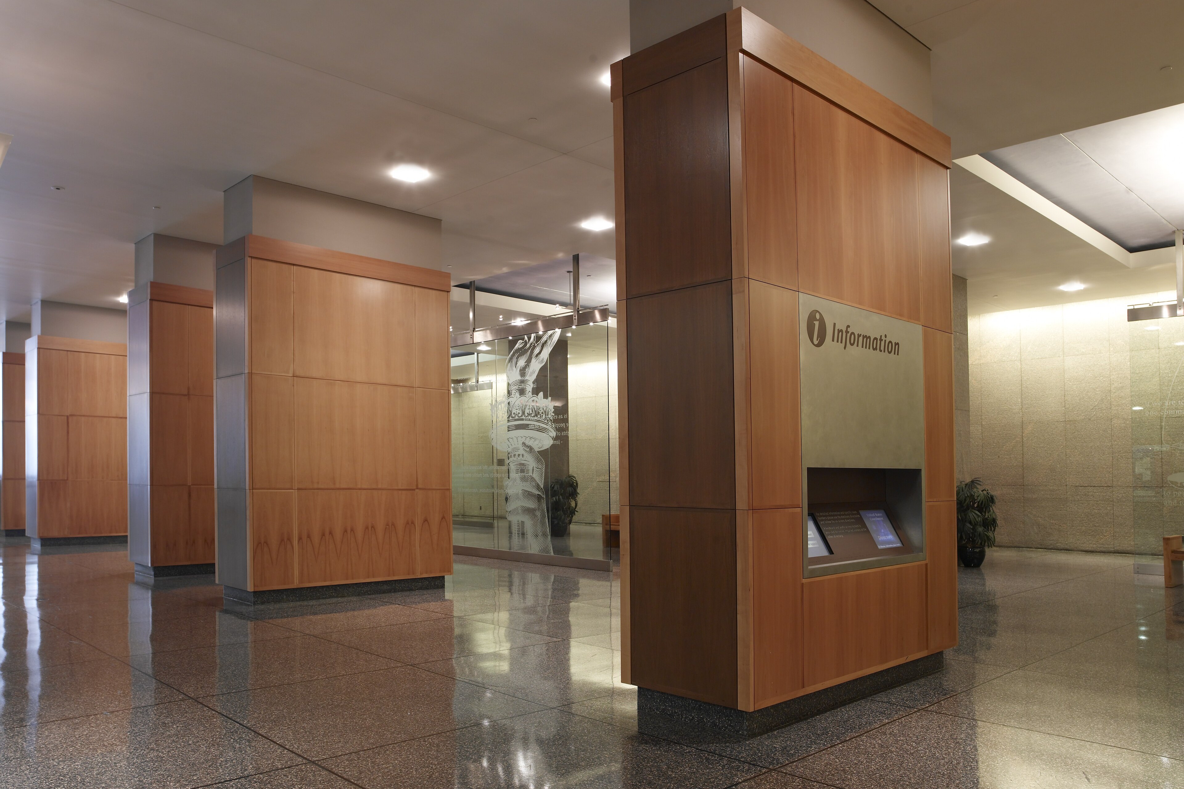 Lobby of the James A. Byrne U.S. Courthouse in Philadelphia with wood-paneled columns and a granite floor