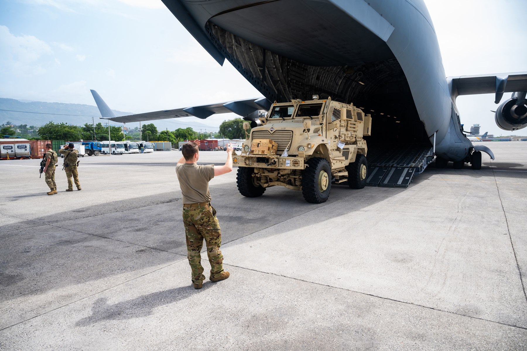 A U.S. Air Force loadmaster directs an armored MRAP vehicle off a C-17 at Toussaint Louverture International Airport in Port-au-Prince, Haiti