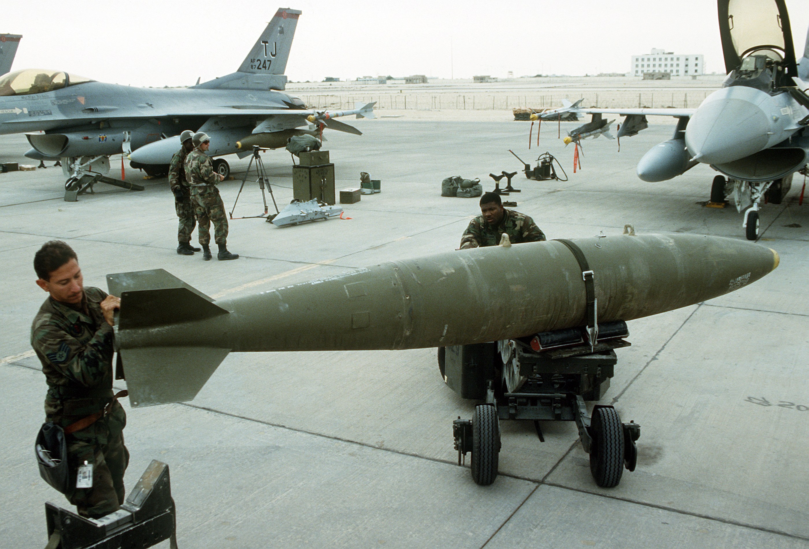 U.S. Air Force airmen load MK-84 2,000-pound bombs onto an F-16 fighter jet during Operation Desert Storm