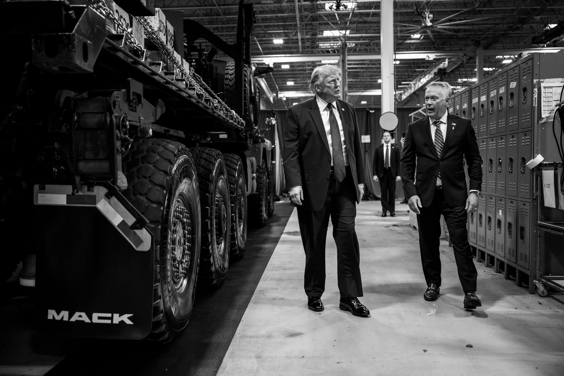 President Donald Trump walks past a Mack truck with Mack Trucks president Stephen Roy at the company's Macungie, Pennsylvania plant