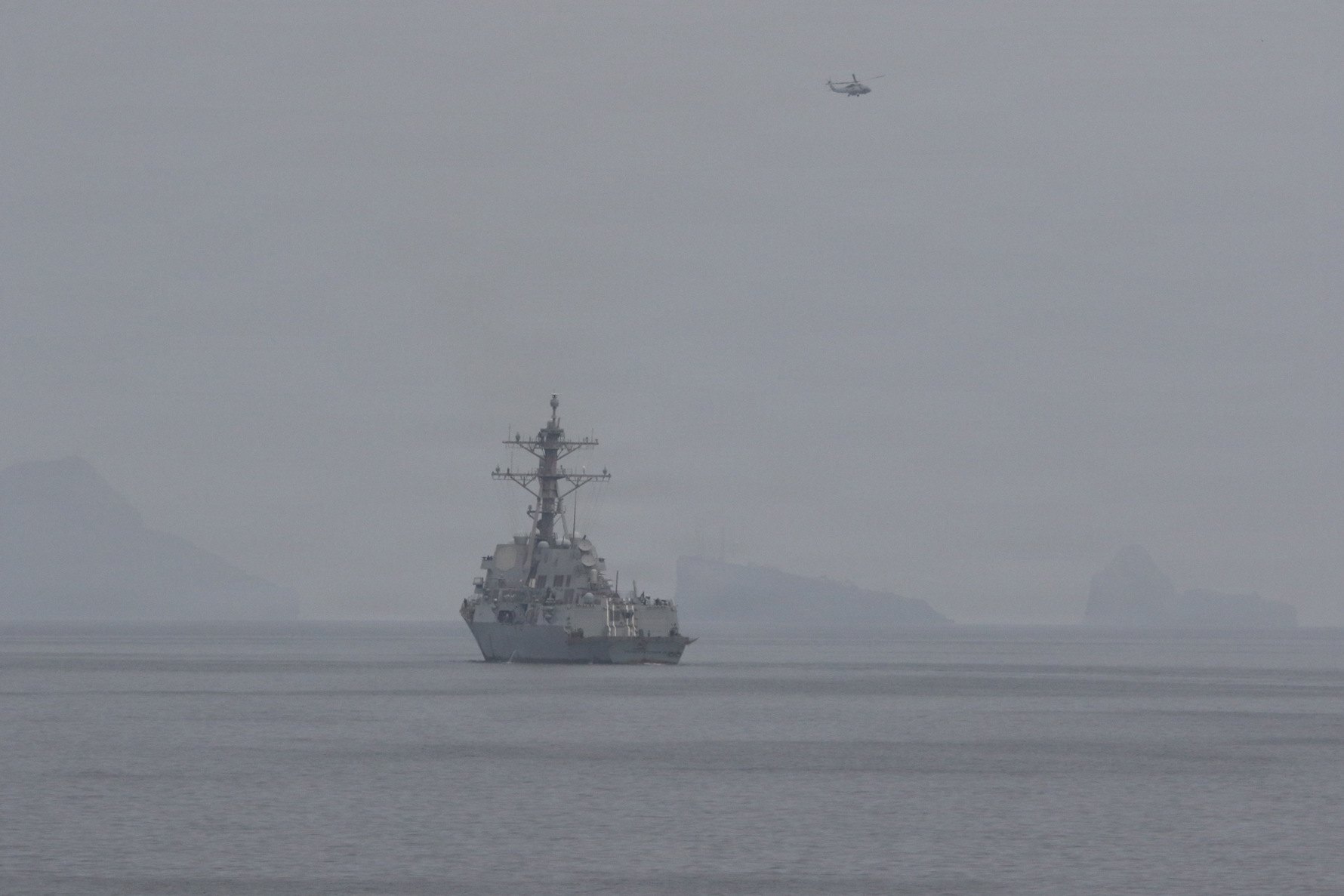 A U.S. Navy guided-missile destroyer operating in the Strait of Hormuz in hazy conditions