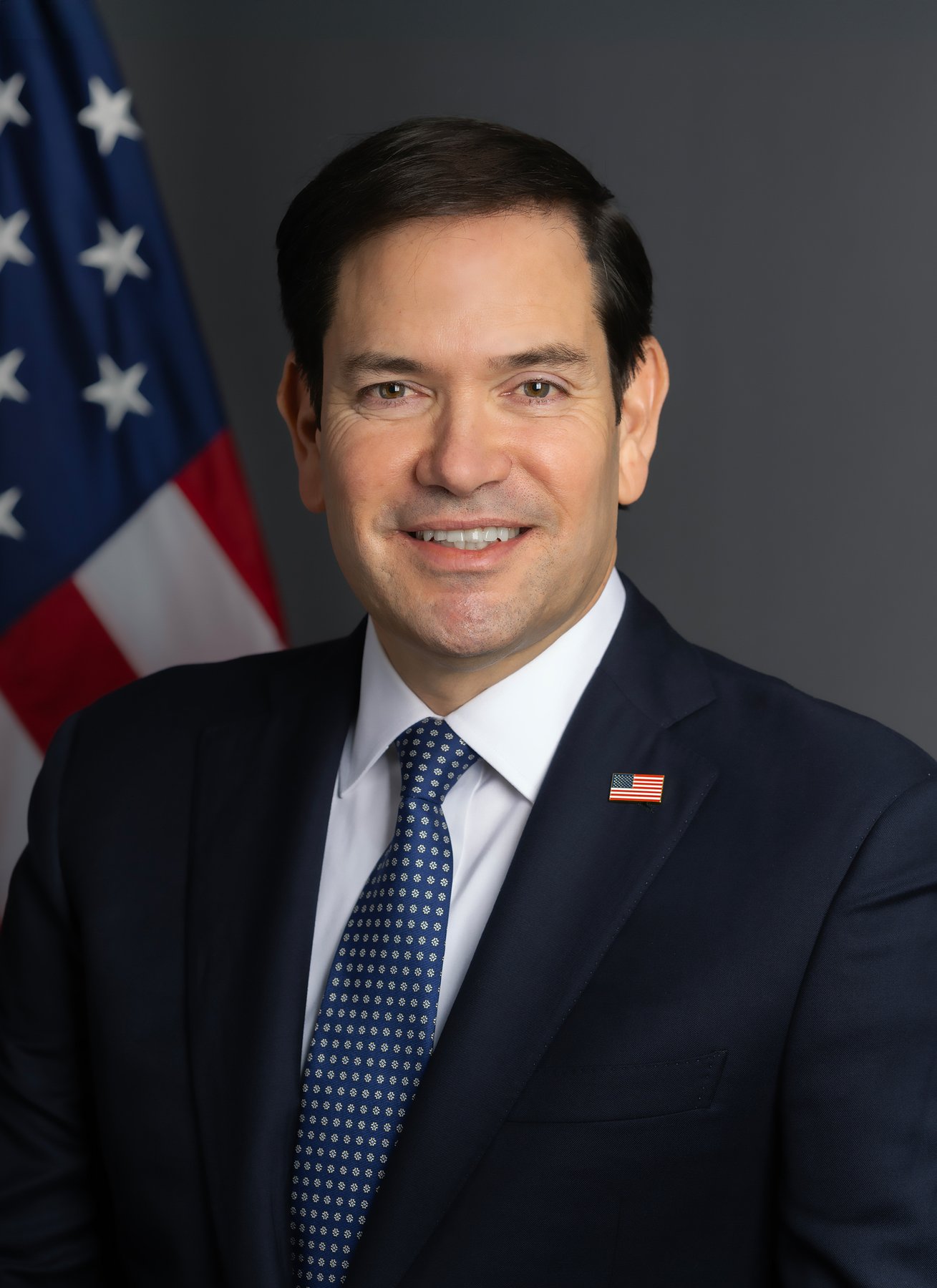 Official portrait of Secretary of State Marco Rubio in front of an American flag