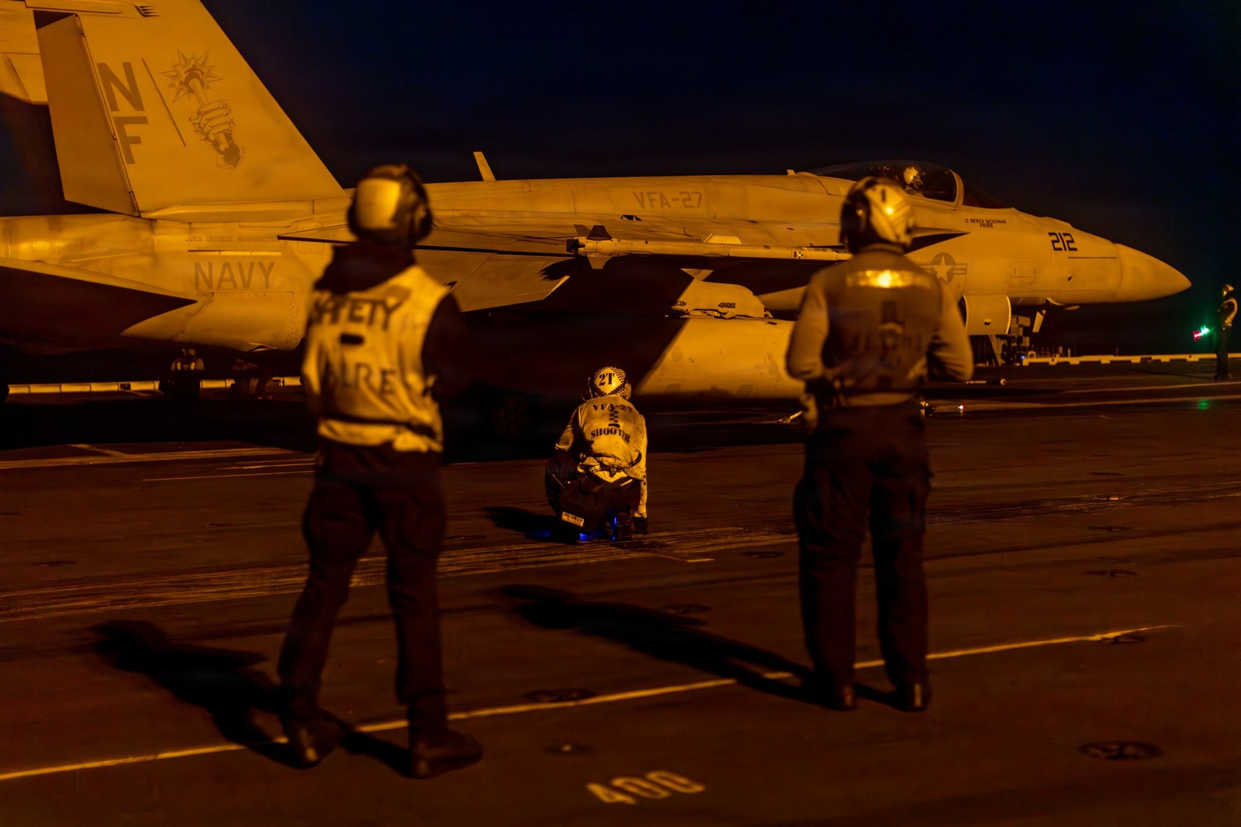 U.S. Navy sailors conduct night pre-flight checks on an F/A-18 Super Hornet on the flight deck of the aircraft carrier USS George Washington