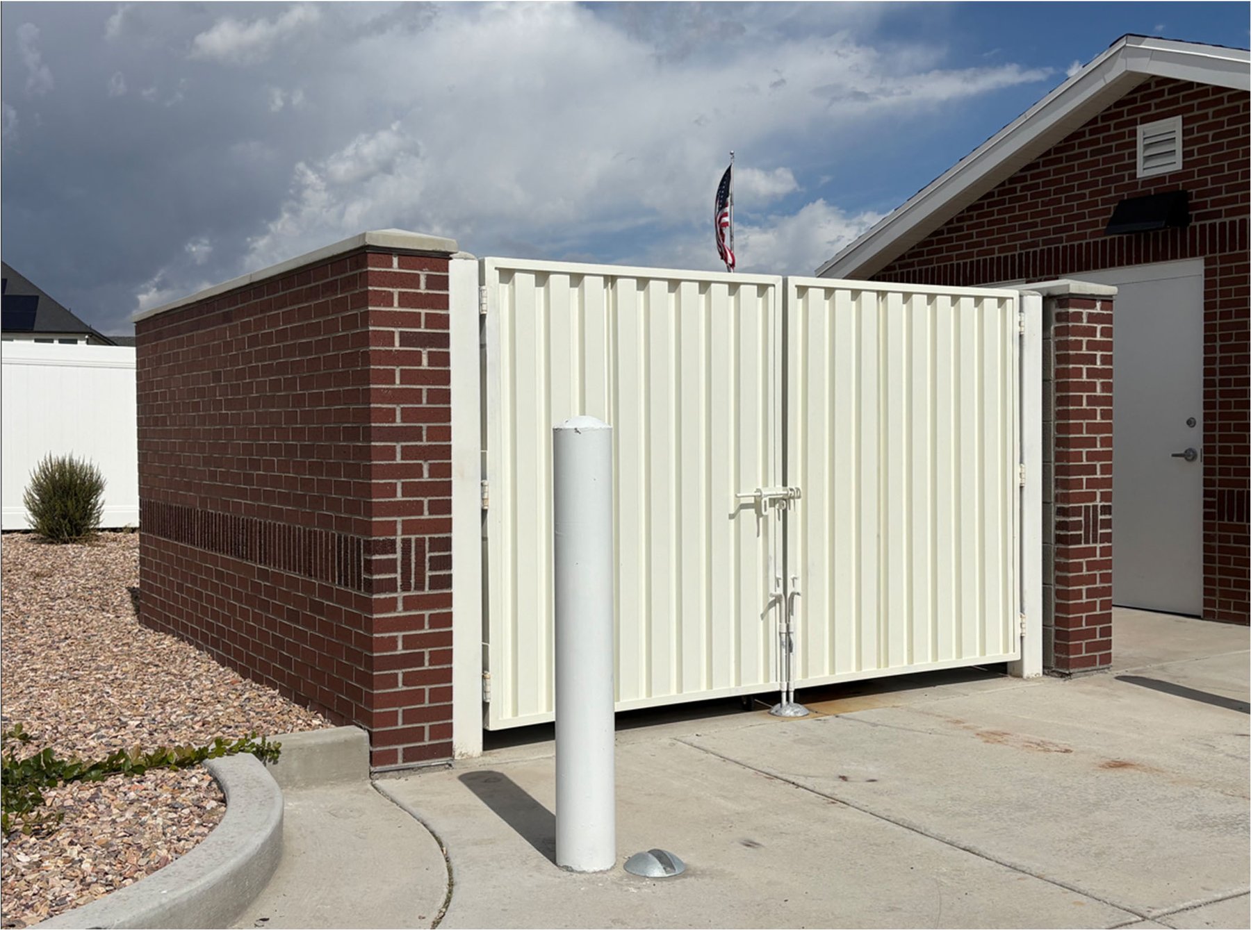Gated brick dumpster enclosure in a church parking lot in Eagle Mountain, Utah, photographed as a federal court exhibit