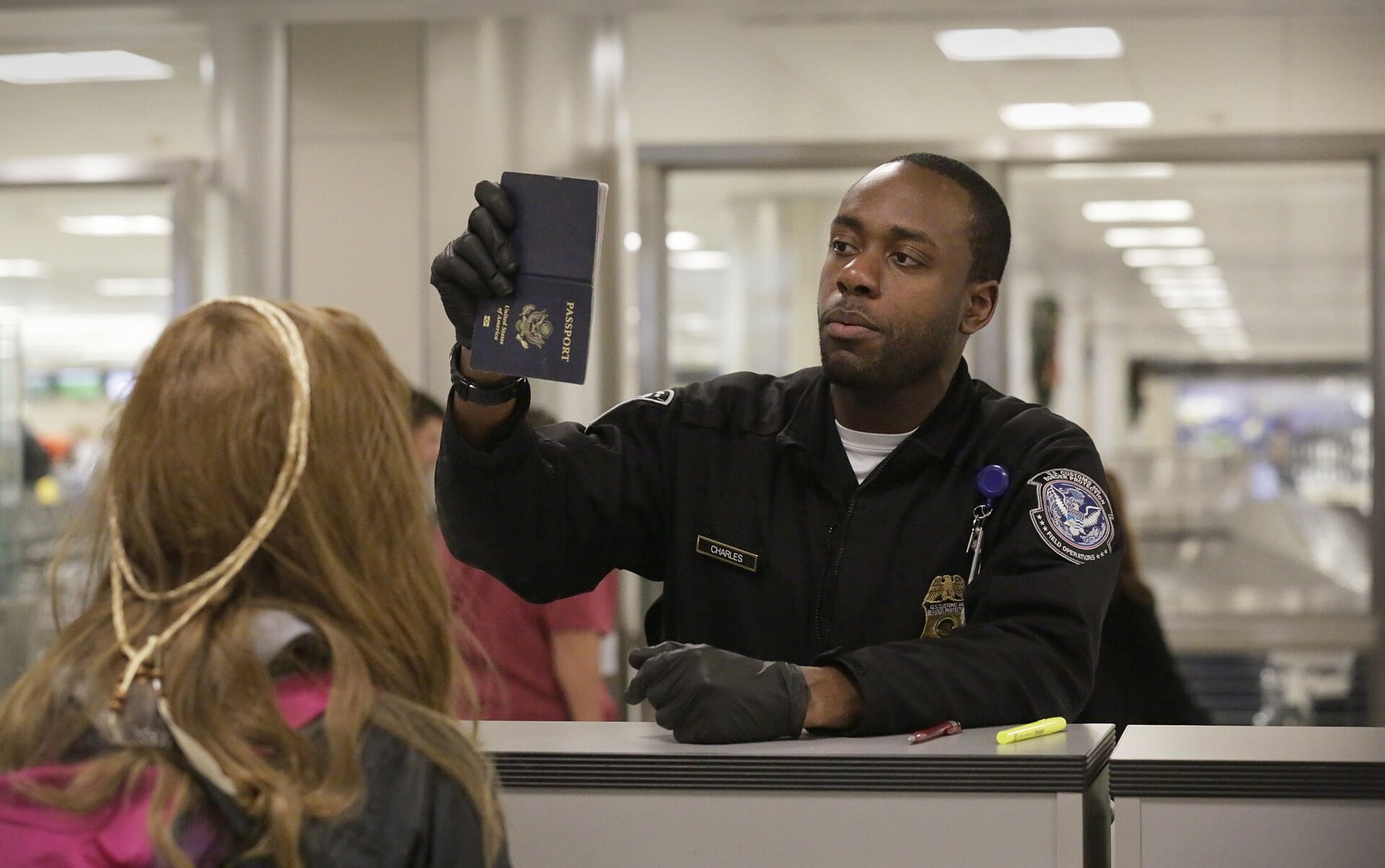 A U.S. Customs and Border Protection officer inspects a passport at Dulles International Airport