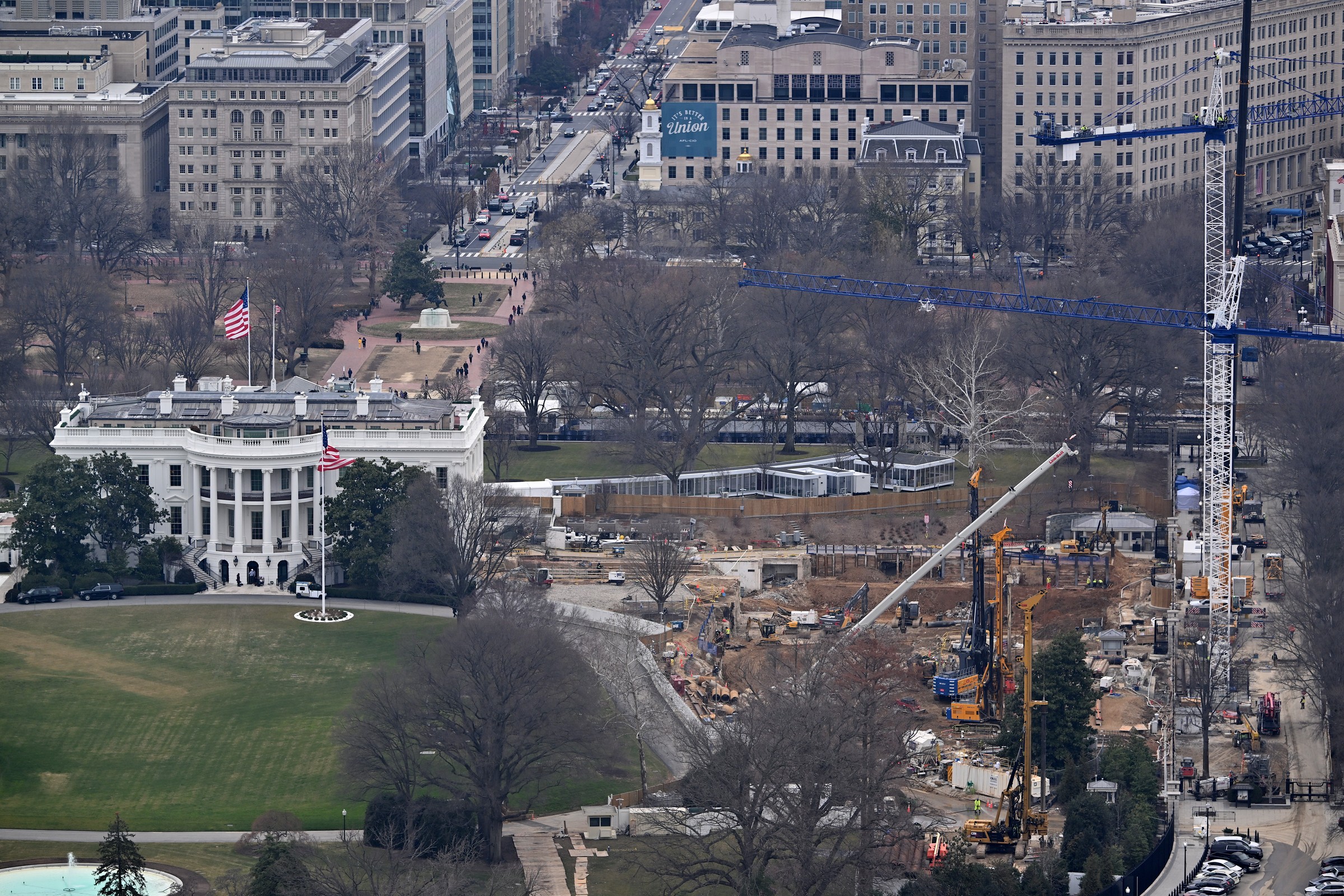 Aerial view of the White House with the East Wing demolished and the ballroom construction site active, cranes and excavators working on the east side of the grounds