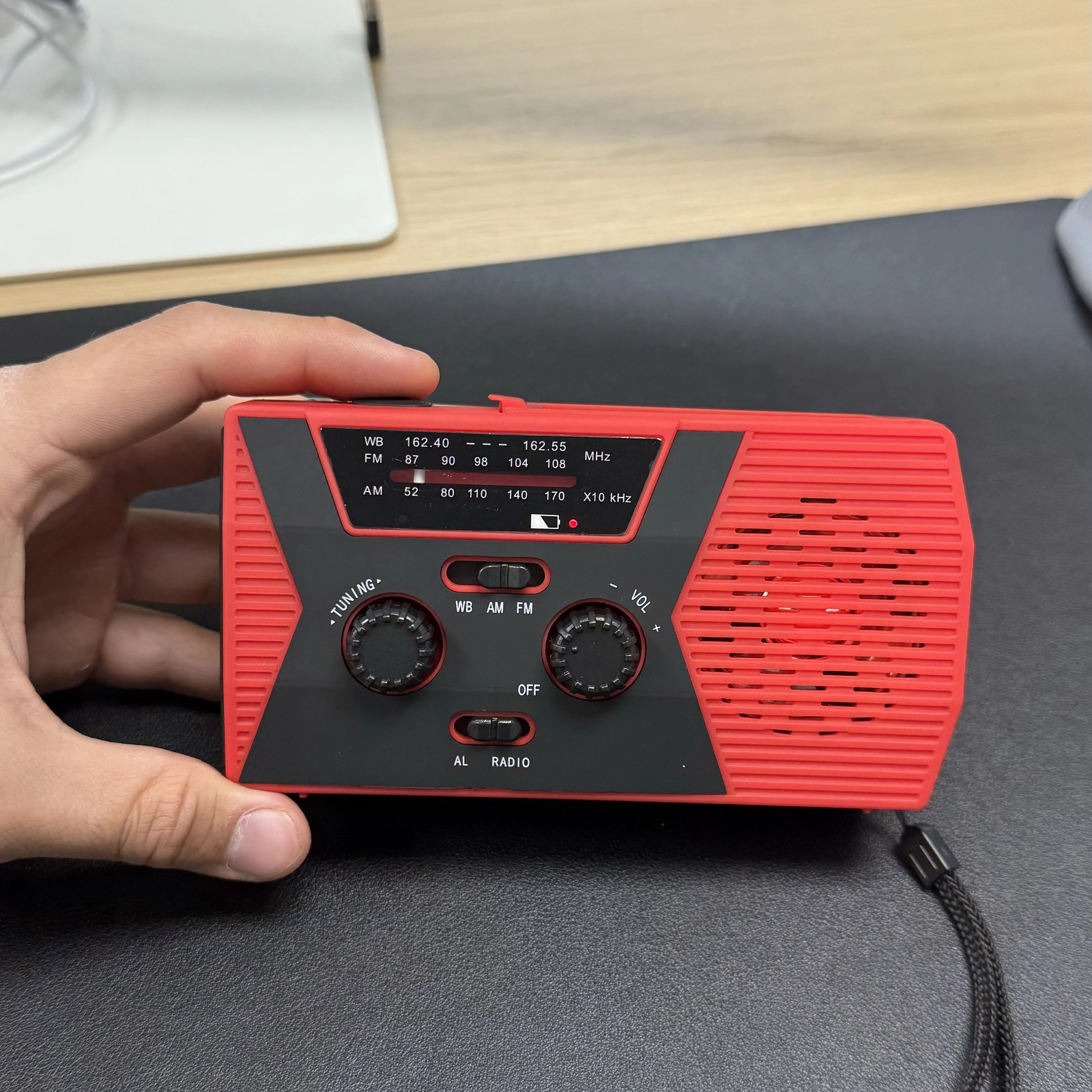 The Tacright Emergency Radio held in one hand to show its size